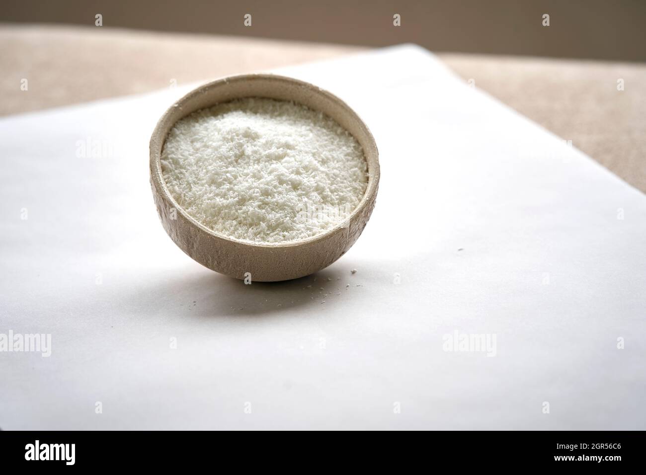 Ansicht von geriebener Kokosnuss in Keramikschale auf weißem Hintergrund. Stockfoto