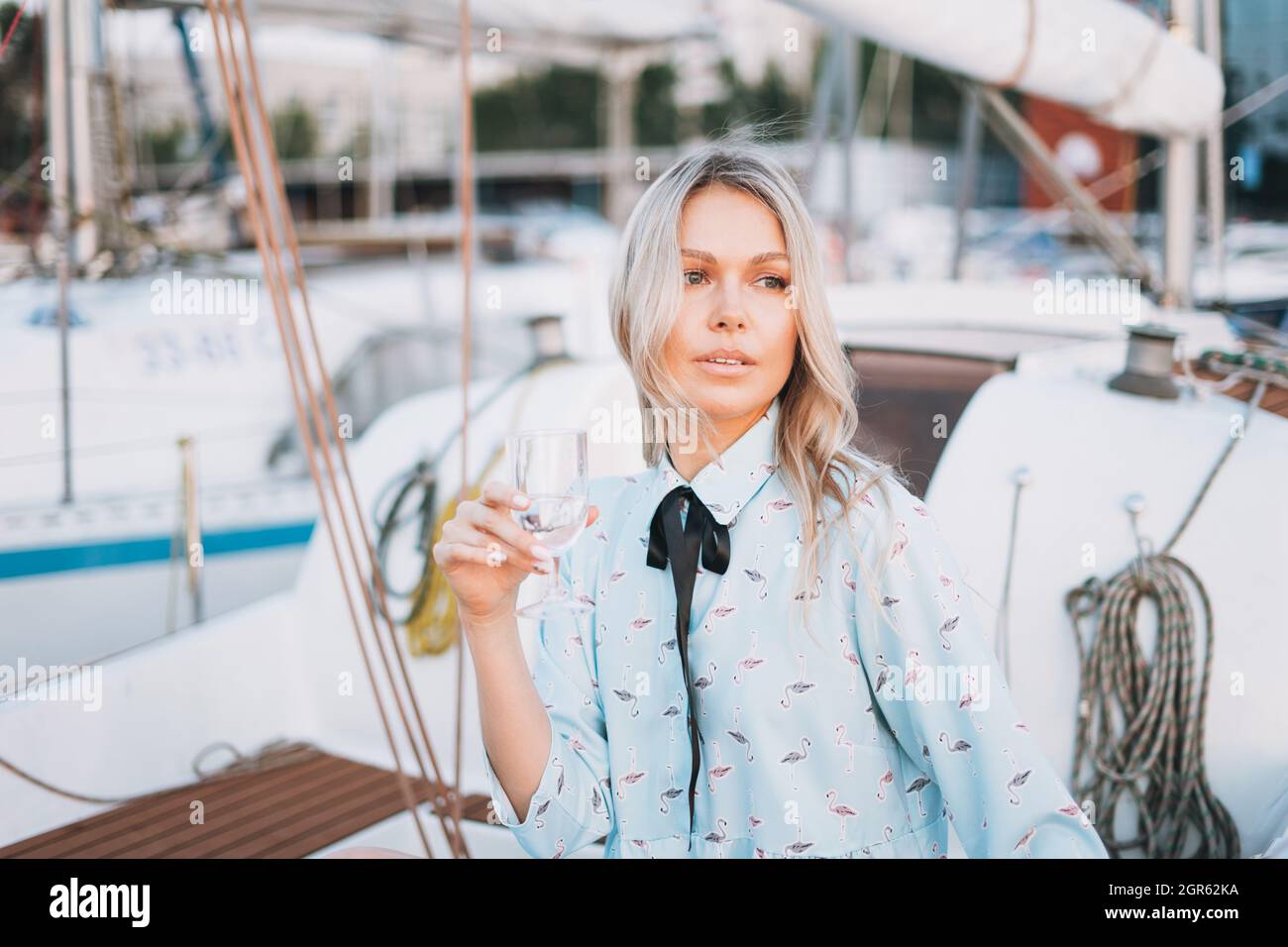 Schöne Blonde Junge Frau In Blauem Kleid Mit Glas Soda Auf Dem Boot Am Pier  In Der Sonnenuntergangszeit Stockfotografie - Alamy