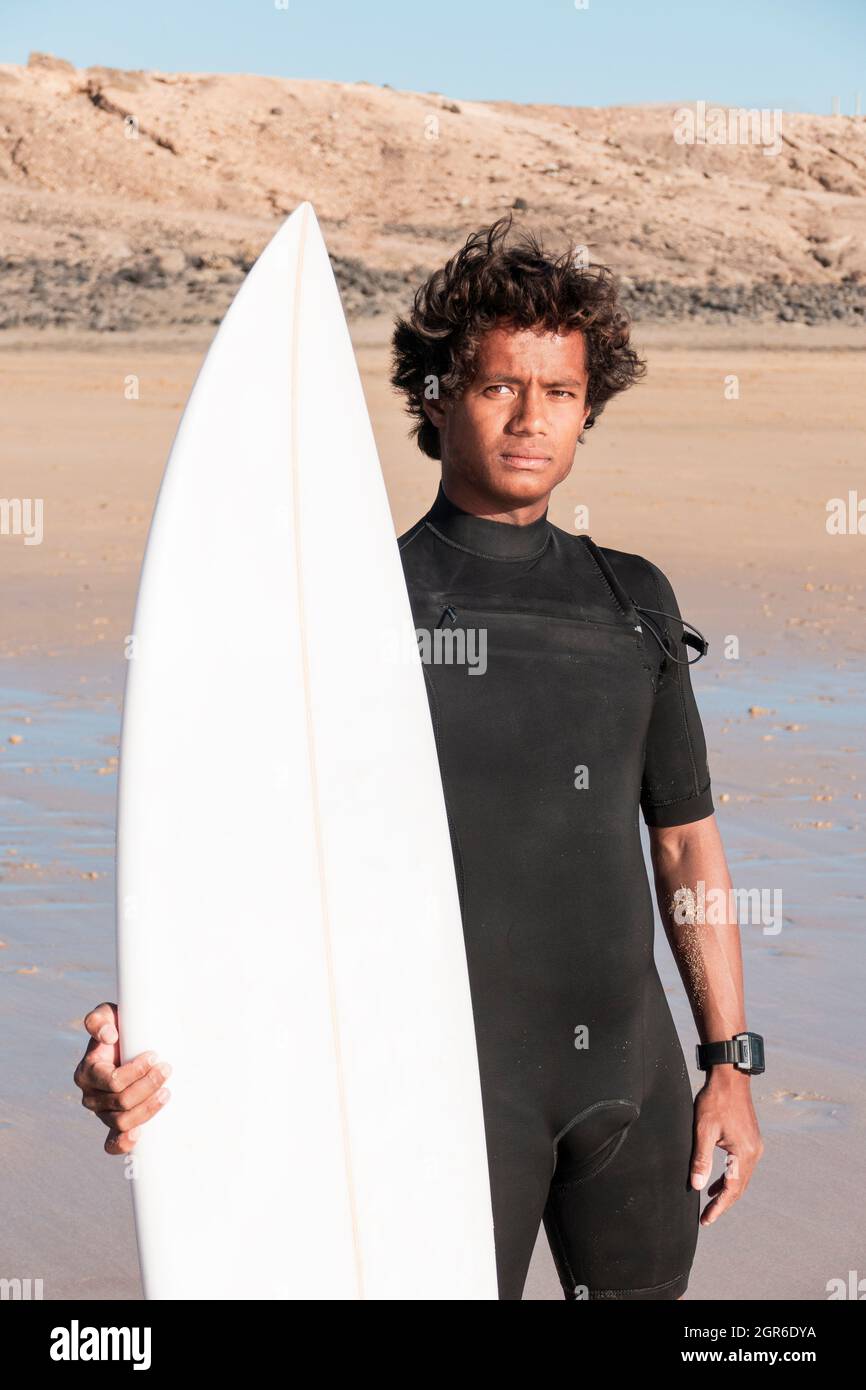 Das junge madagassische Surferportrait mit seinem Surfbrett, das am Strand steht Stockfoto