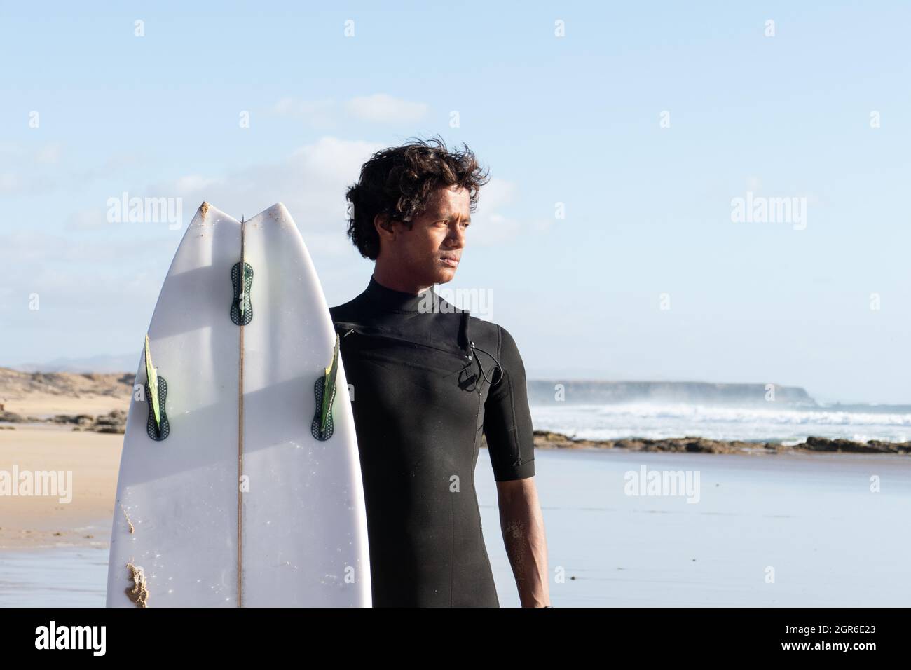 Das junge madagassische Surferportrait mit seinem Surfbrett, das am Strand steht und die Wellen beobachtet Stockfoto