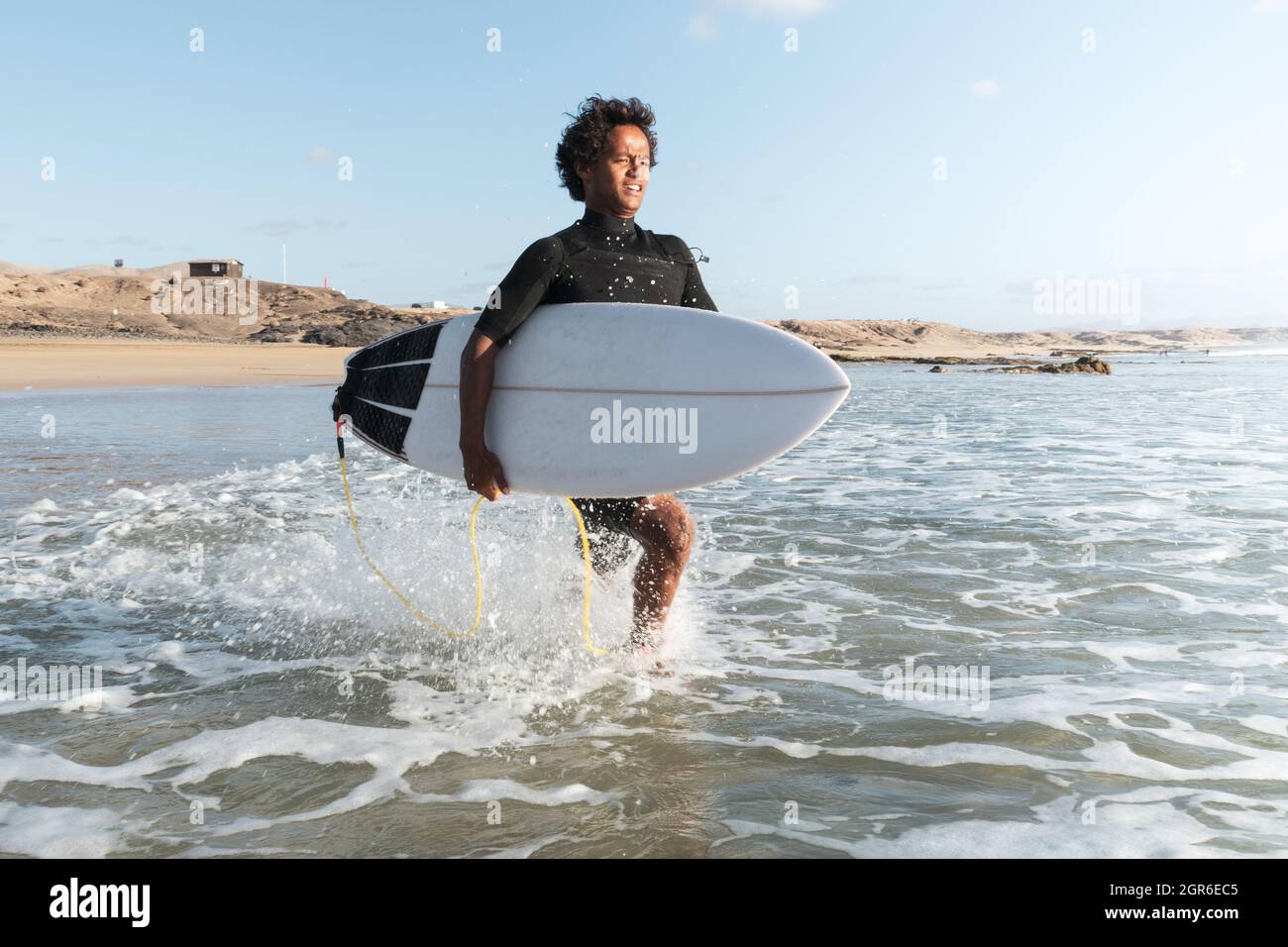 Junger afrikanischer, madagassischer Surfer, der am Strand zu den Wellen läuft Stockfoto