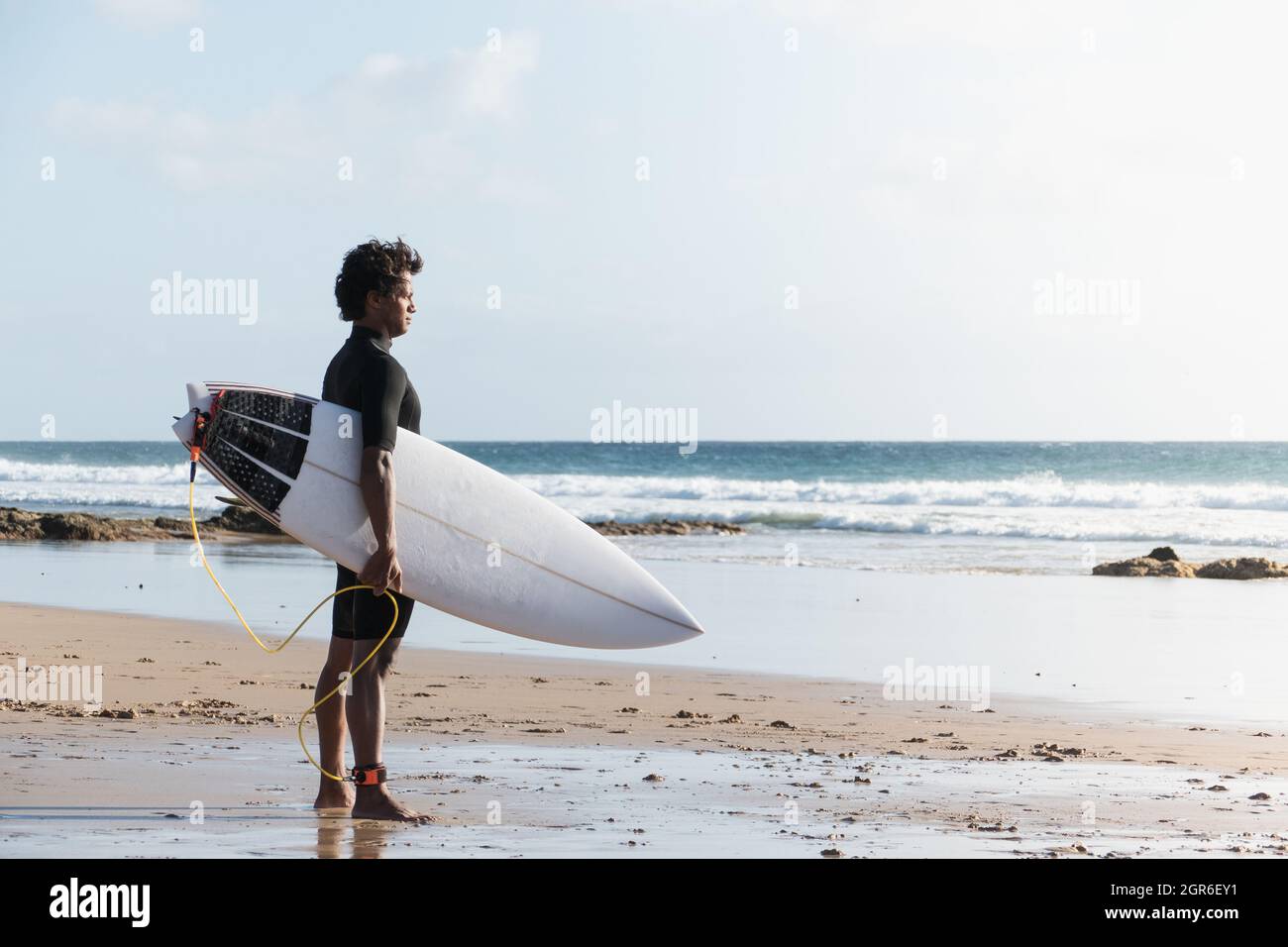 Junger afrikanischer, madagassischer Surfer, der die Wellen am Strand beobachtet Stockfoto