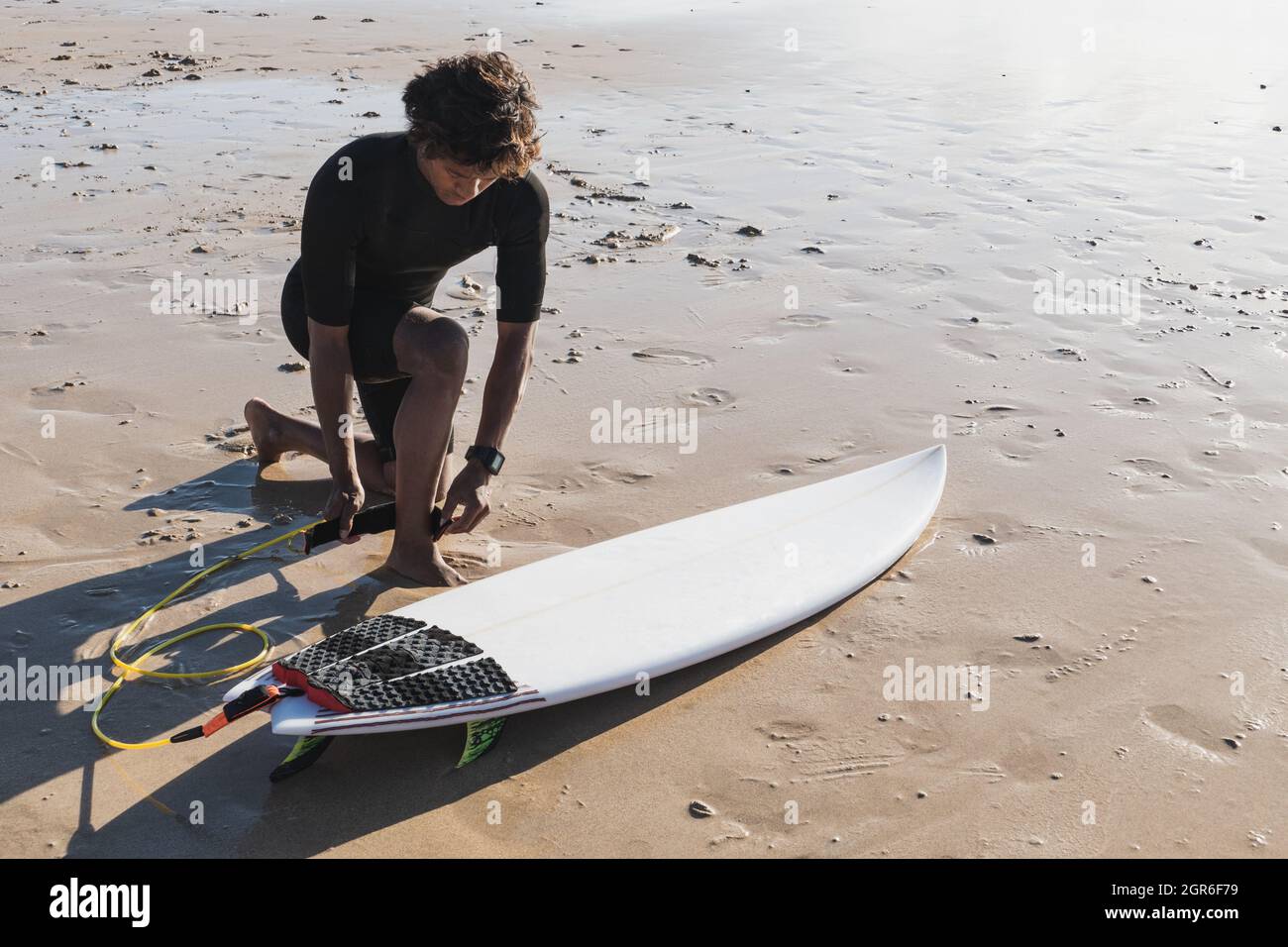 Junger Surfer, der Surfleine an seinem Knöchel befestigt Stockfoto