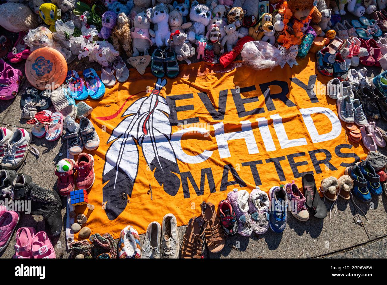 Ein „Every Child Matters“-Banner ist von Kinderschuhen und Spielzeug umgeben. Sie repräsentieren First Nations-Kinder, die an Wohnschulen starben. Stockfoto