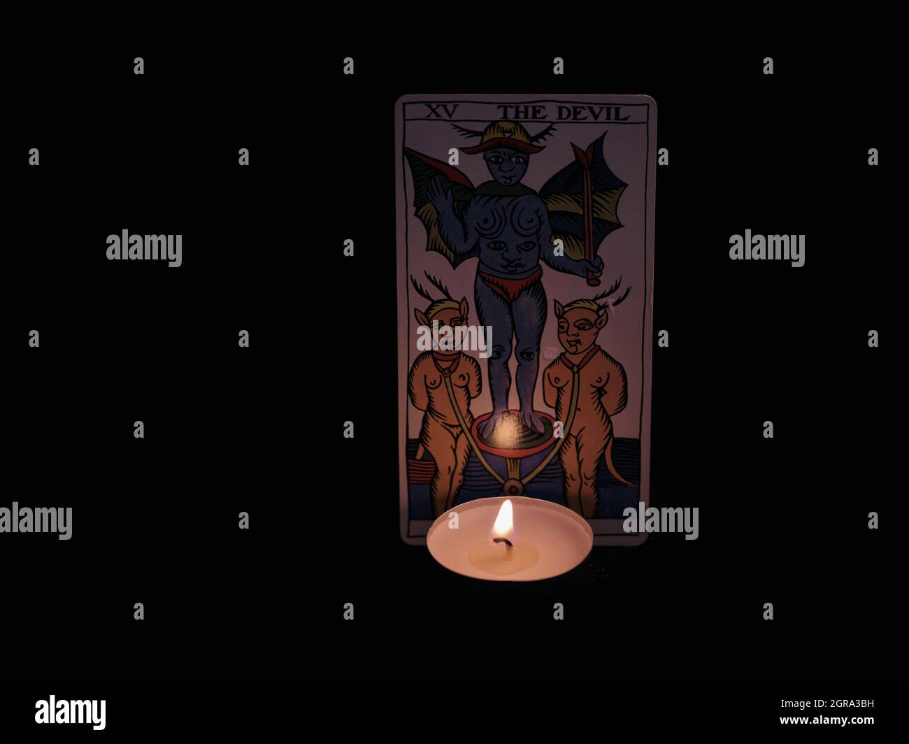 Eine einzelne große Arcana Tarot-Karte isoliert auf schwarzem Hintergrund. Der Teufel. Kerzenlicht Stockfoto