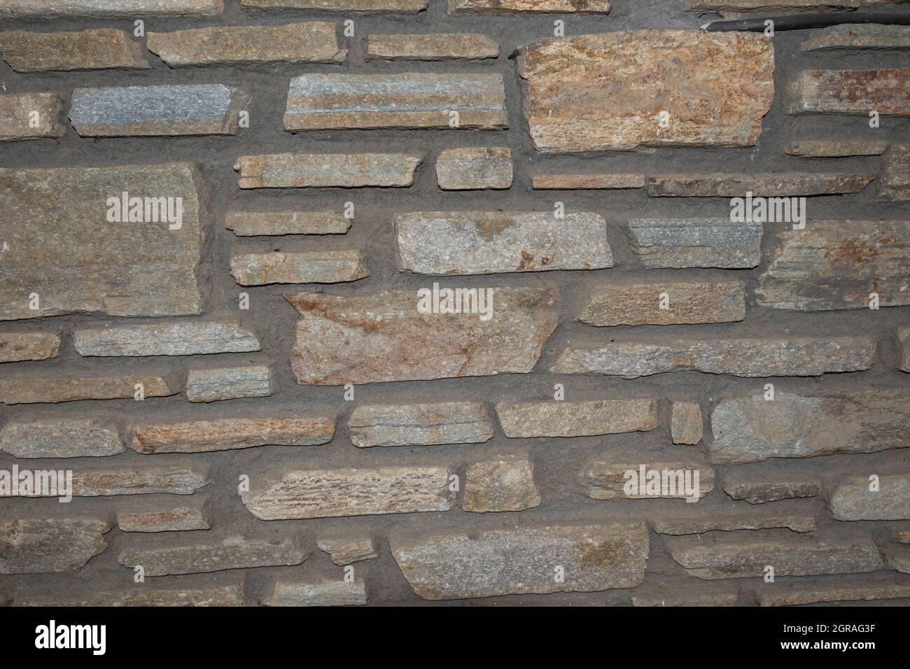 Rustikale Wand aus unebenen Steinen Stockfoto