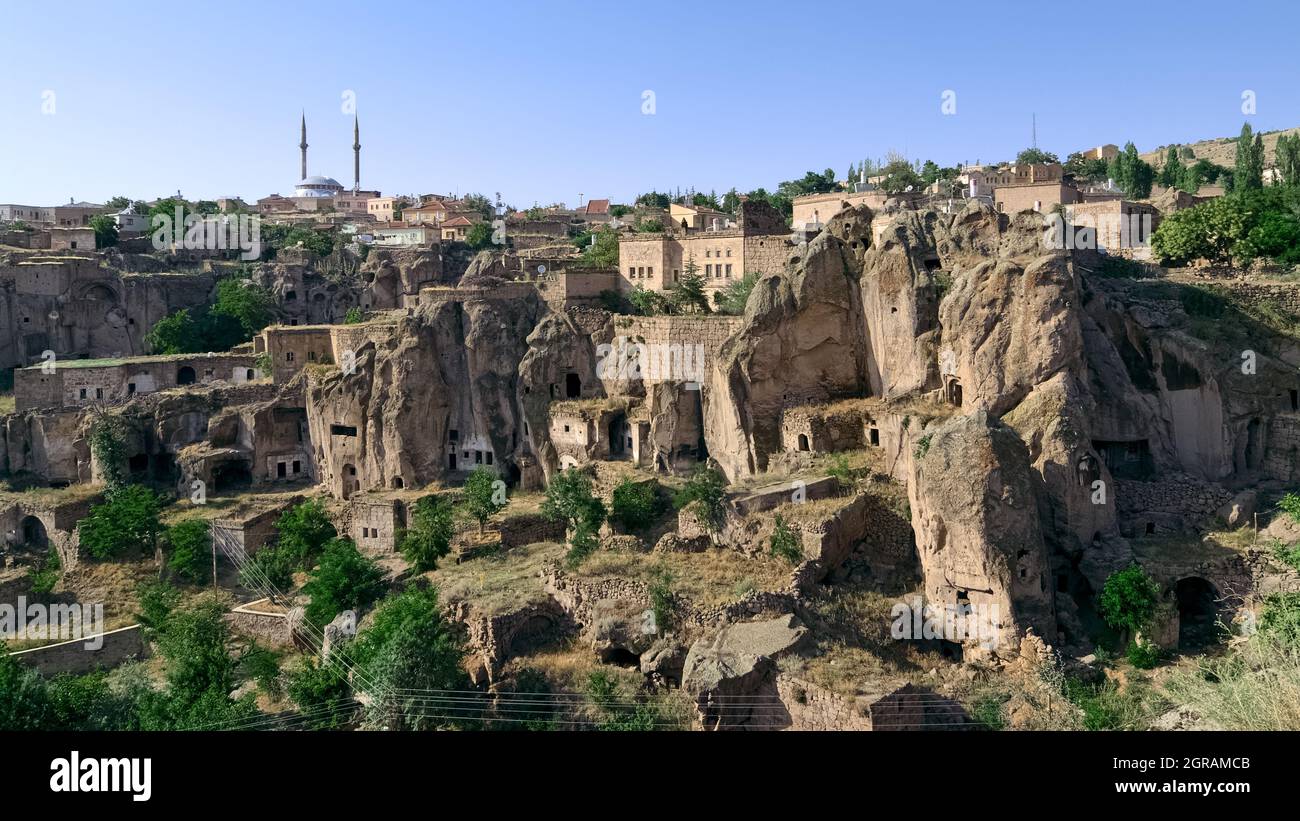 Ländliche Stadt des traditionellen Landes in der Türkei Moschee von Guzelyurt und Felsen geschnitten Höhlenhäuser in den typischen vulkanischen Felsen von Kappadokien geschnitzt Stockfoto