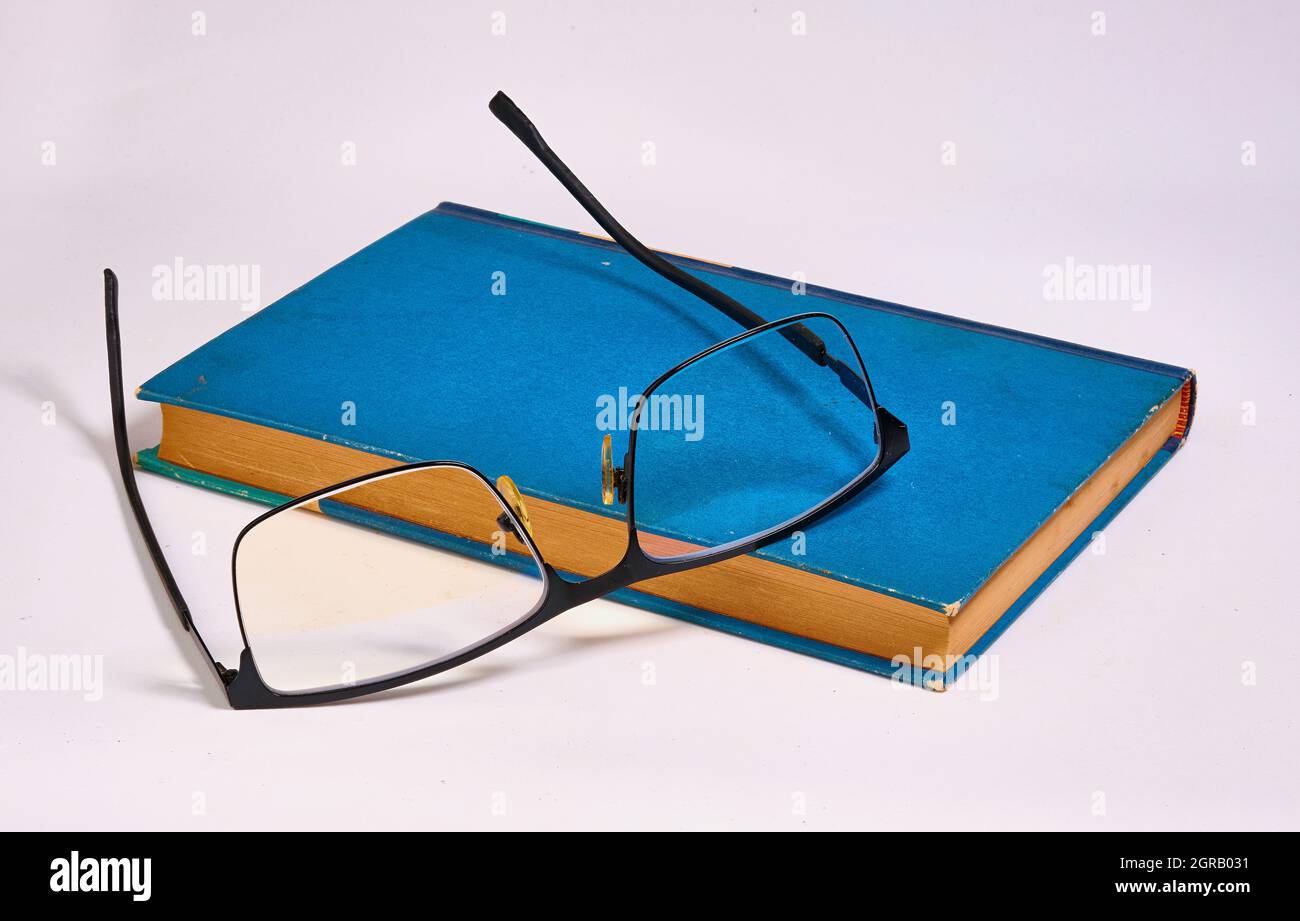 Die Gläser wurden entfernt und auf ein blaues Buch gelegt. Weißer Hintergrund Stockfoto