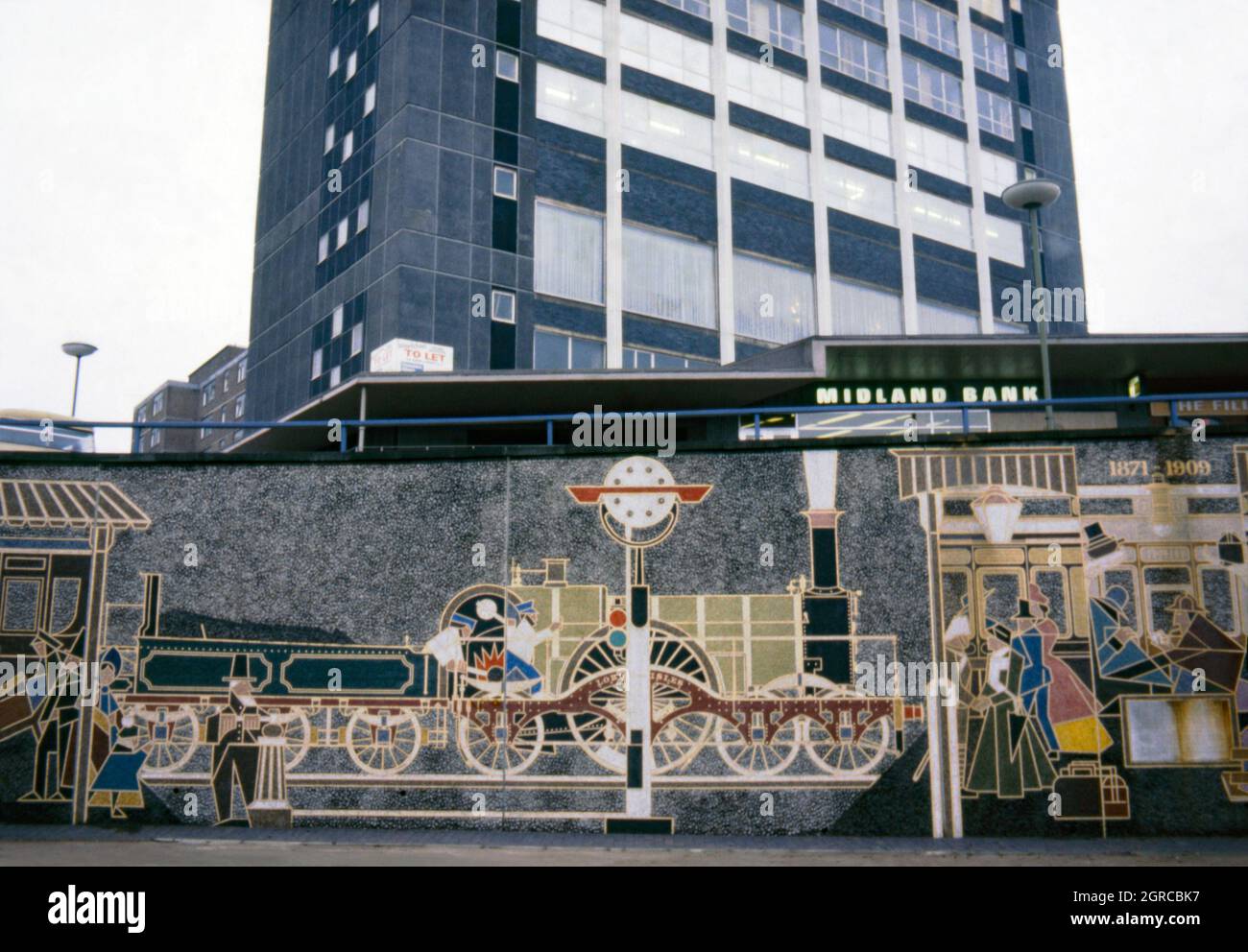 Eine Ansicht des ursprünglichen ‘History of Snow Hill’, ein Wandgemälde von Kenneth Budd aus dem Jahr 1968, das 1978 im Queensway des St Chad, Birmingham, England, Großbritannien, gelegen wurde. Das Wandgemälde feierte die Geschichte des Bahnhofs Birmingham Snow Hill und der Great Western Railway, dem Unternehmen, das den Zugverkehr zwischen London Paddington und Snow Hill Betrieb. Das Wandgemälde wurde 2007 zerstört, als das Gebiet sanierte. 2013 hat Kenneth Budds Sohn Oliver Budd das Wandbild in Miniatur in der Nähe neu gestaltet. Dieses Bild stammt von einem alten Amateur-35-mm-Farbtransparenz – einem Vintage-Foto aus den 1970er Jahren. Stockfoto