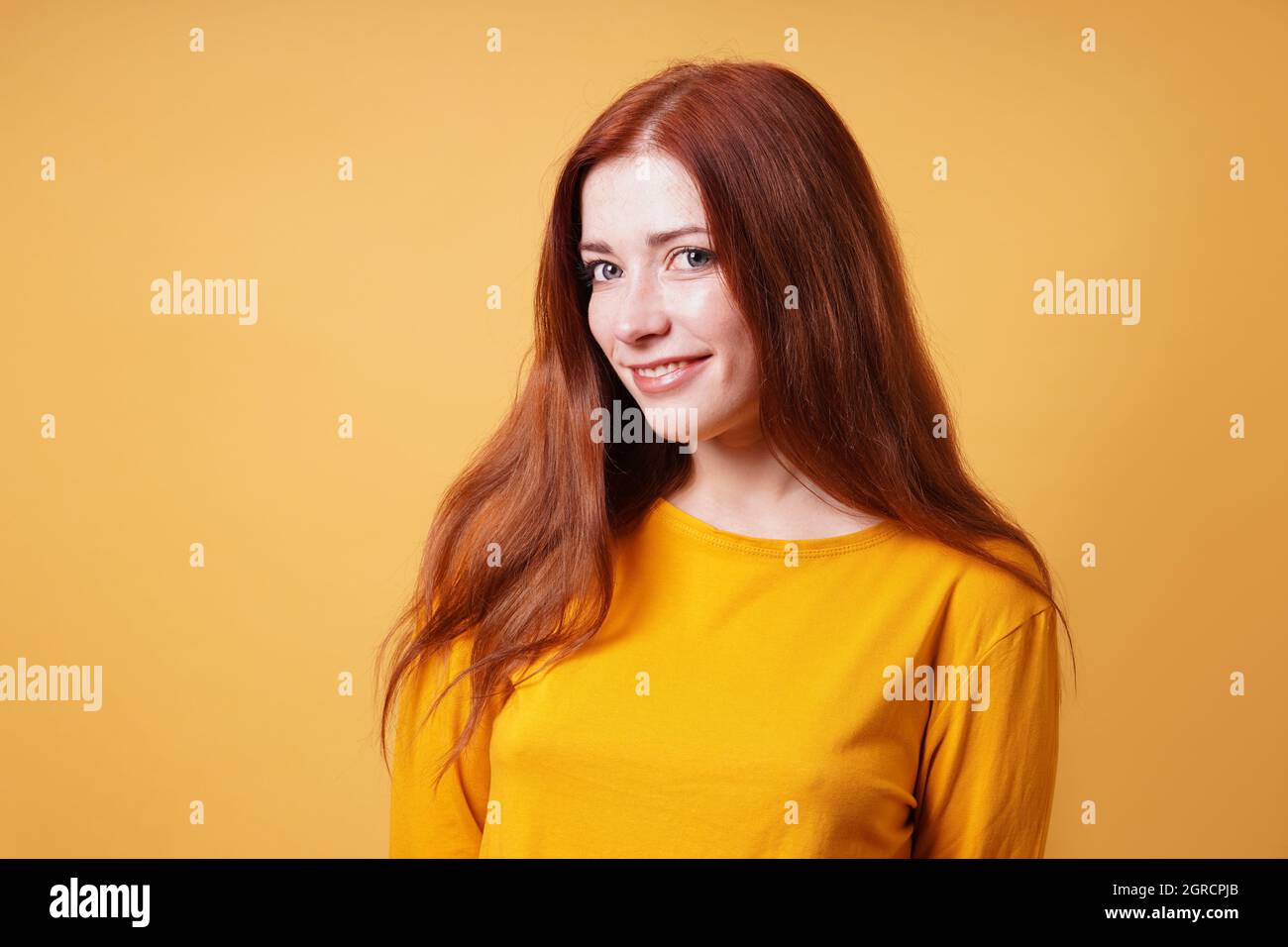 Glückliche junge Frau mit langen roten Haaren lächelnd Stockfoto
