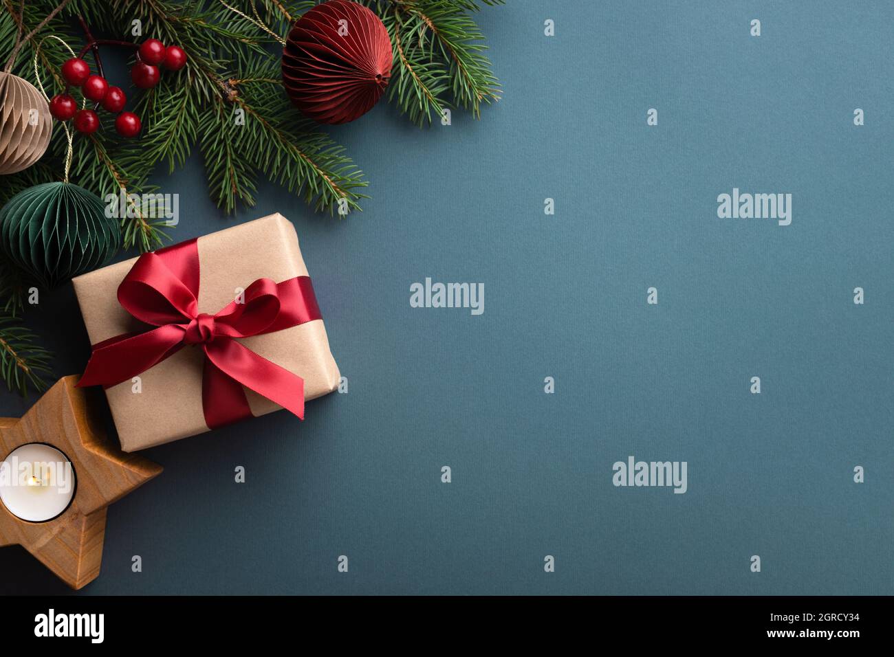 Dunkeltürkisfarbener Hintergrund mit Weihnachts-Geschenkbox und Kerzenhalter aus Holz. Stockfoto