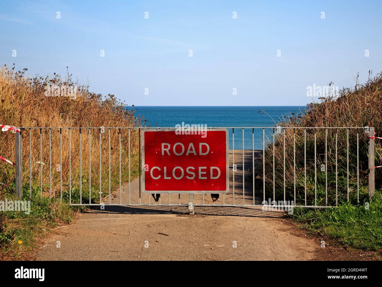 A Road Closed Schild und Barriere am Ende einer kleinen Straße, die durch Küstenerosion in Happisburgh, Norfolk, England, Großbritannien, dem Meer verloren ging. Stockfoto