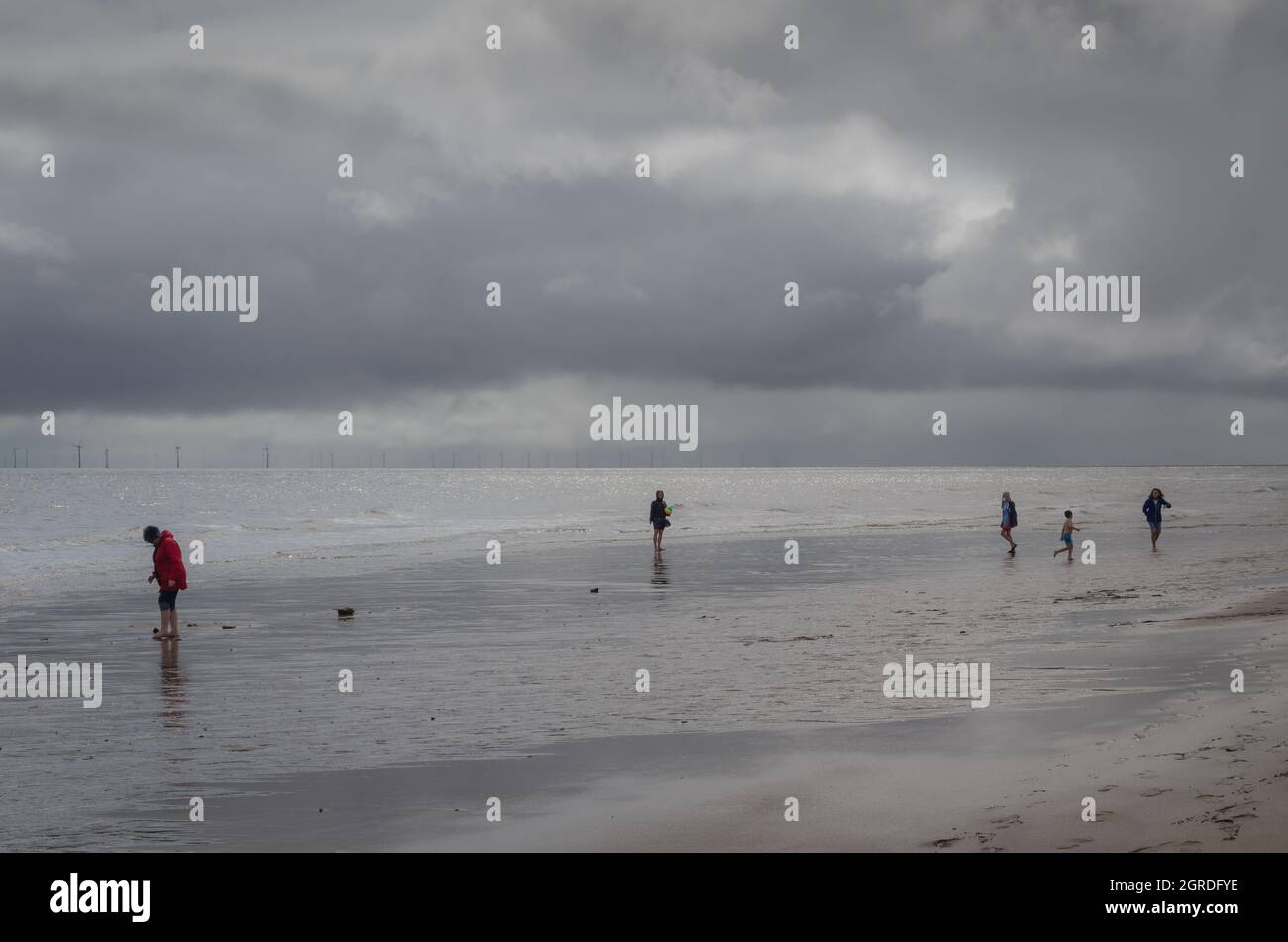 Menschen am Strand bei bewölktem Wetter Stockfoto