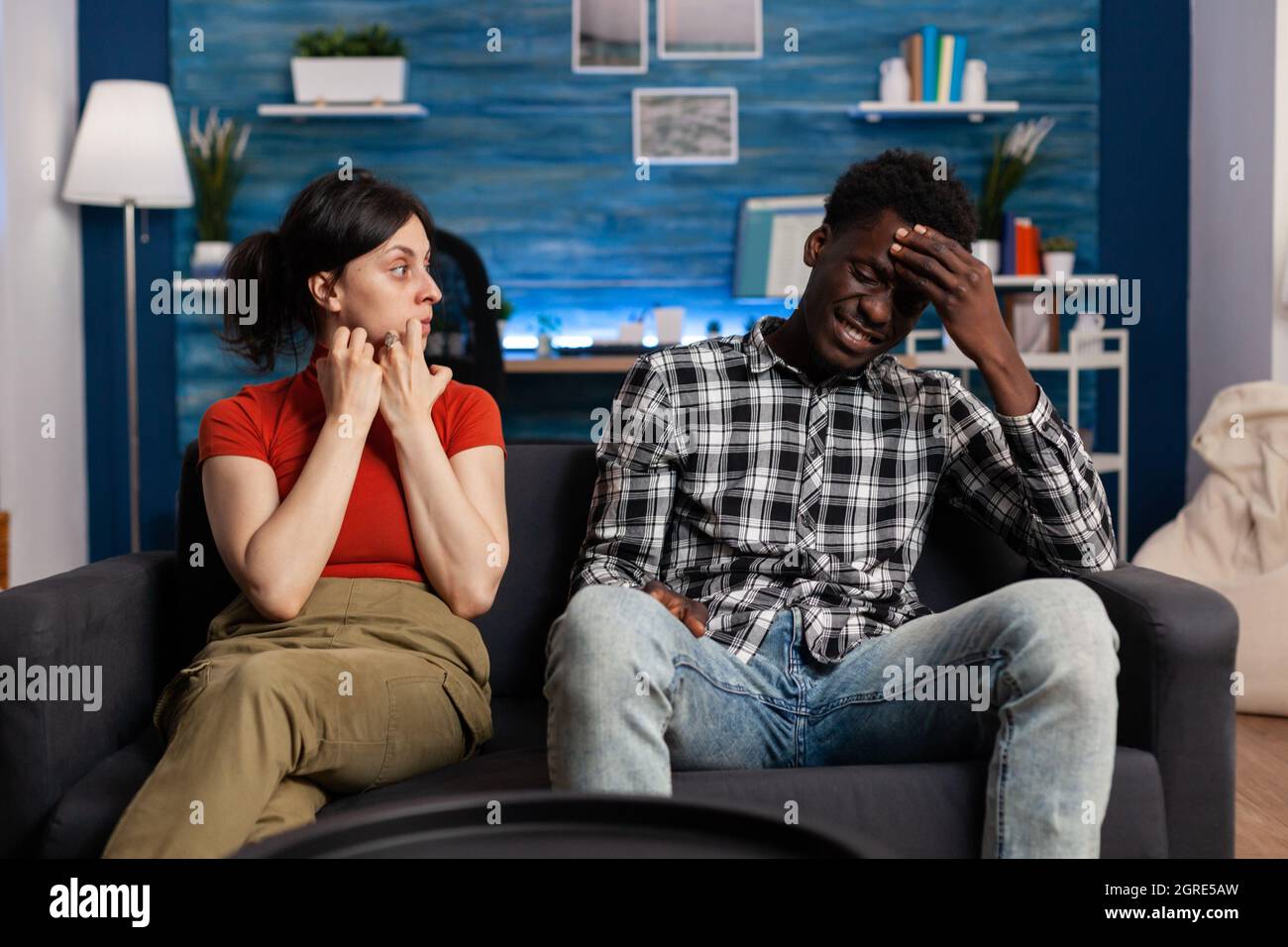 Interracial paar immer in Streit sitzen auf Couch. Irragene gemischte Rennpartner kämpfen und Beziehungsprobleme haben. Kaukasische Frau, die afroamerikanischen Mann anschrie Stockfoto