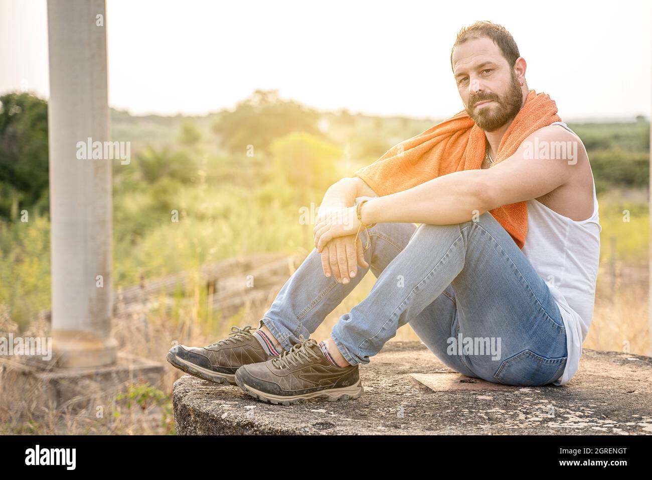 Sexy Mann sitzt in der Natur schaut in die Kamera Stockfoto