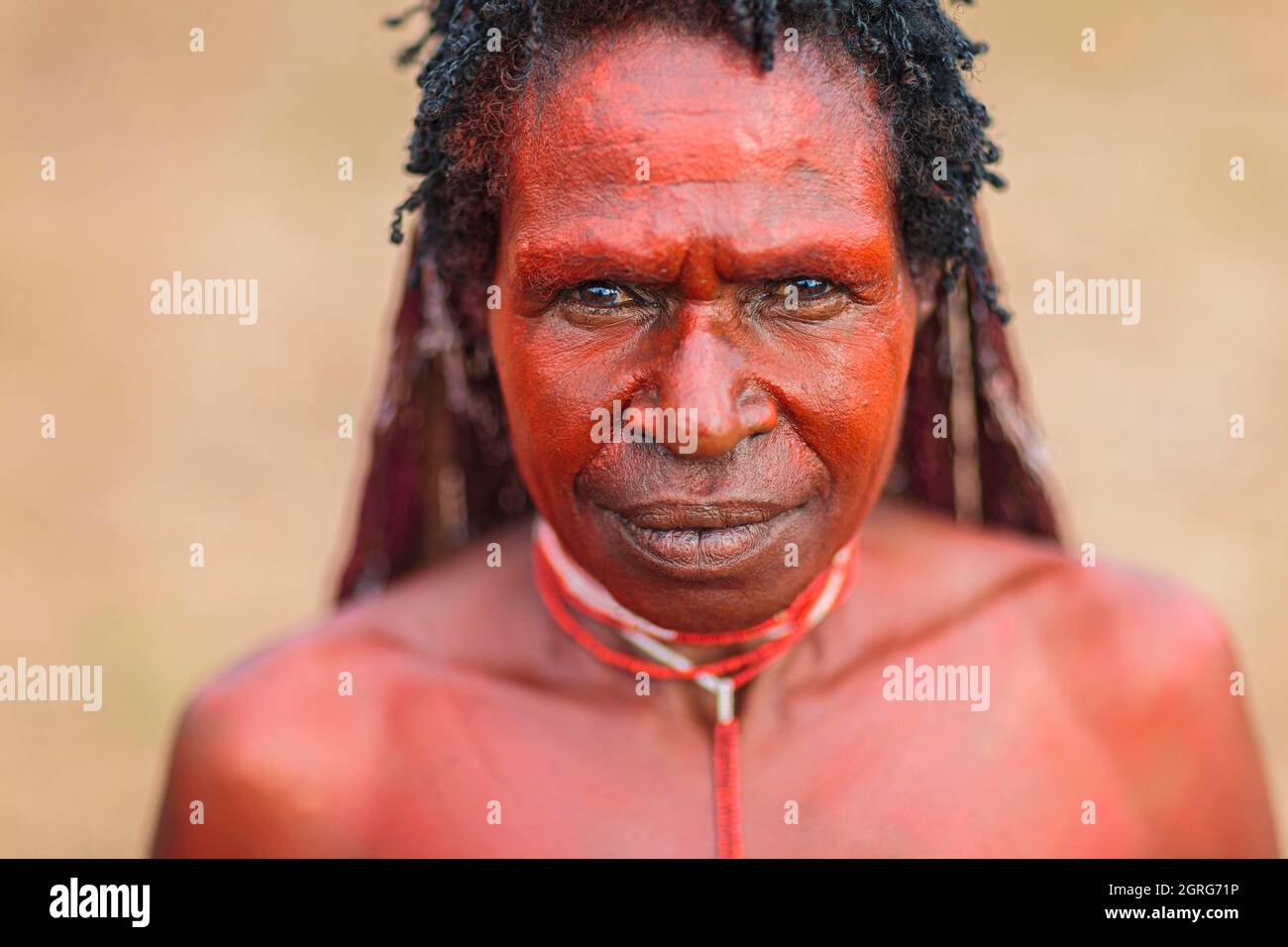 Indonesien, Papua, Stadt Wamena, Porträt einer jungen Dani-Frau, bedeckt mit roter Erde. Baliem Valley Cultural Festival, jedes Jahr im August kommen Stämme zusammen, um uralte Kriegsszenen aufzuführen, Parade und Tanz in traditioneller Kleidung Stockfoto