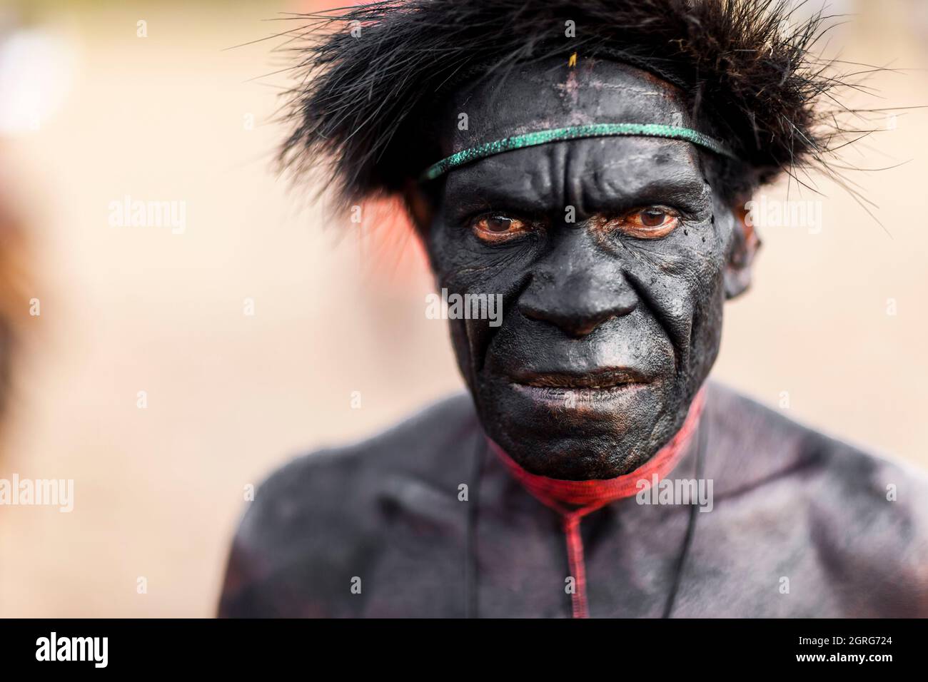 Indonesien, Papua, Stadt Wamena, Porträt eines Dani-Stammes, dessen Gesicht und Körper mit dickem schwarzem Make-up bedeckt sind. Baliem Valley Cultural Festival, jedes Jahr im August kommen Stämme zusammen, um uralte Kriegsszenen aufzuführen, Parade und Tanz in traditioneller Kleidung Stockfoto