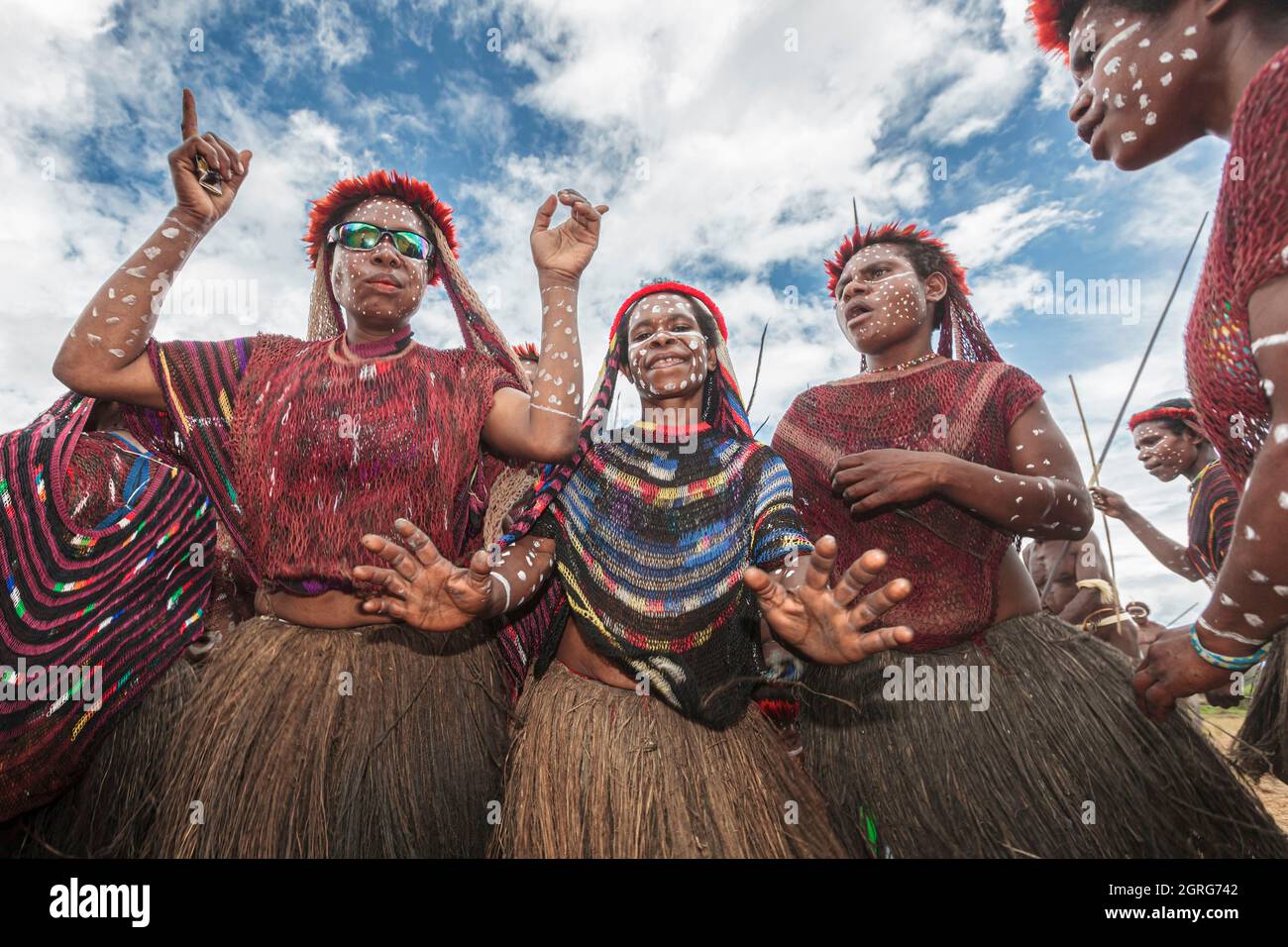 Indonesien, Papua, Stadt Wamena, eine Gruppe junger Mädchen aus dem Dani-Stamm, die tanzen und singen, um Männer zu ermutigen, die in den Krieg gezogen sind. Baliem Valley Cultural Festival, jedes Jahr im August kommen Stämme zusammen, um uralte Kriegsszenen aufzuführen, Parade und Tanz in traditioneller Kleidung Stockfoto