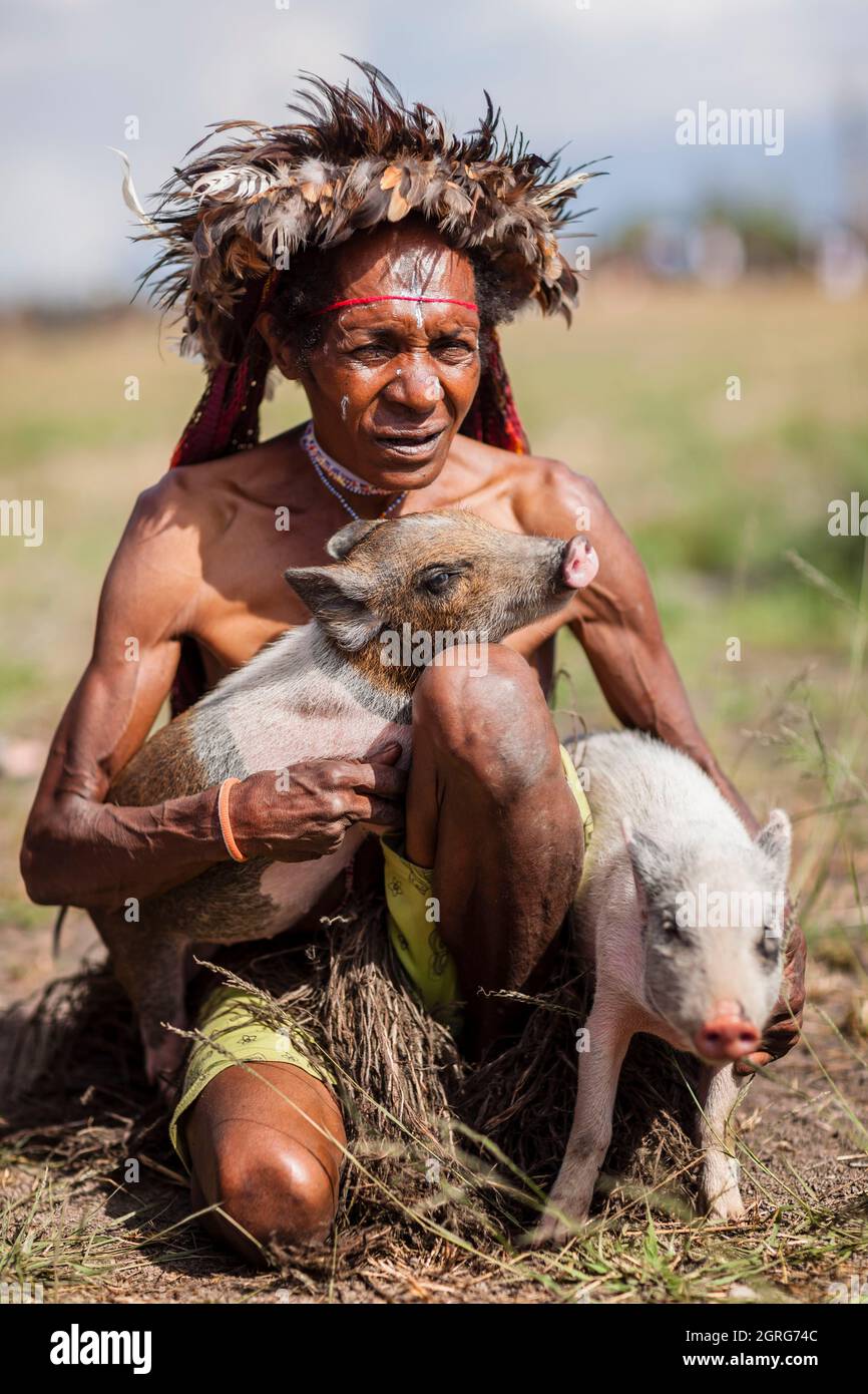 Indonesien, Papua, Stadt Wamena, umarmt eine Dani-Frau aus dem Dani-Stamm ihre kleinen Schweine vor dem Start des Schweinenrennens. Baliem Valley Cultural Festival, jedes Jahr im August kommen Stämme zusammen, um uralte Kriegsszenen aufzuführen, Parade und Tanz in traditioneller Kleidung Stockfoto