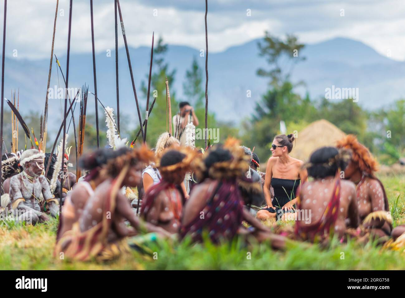 Indonesien, Papua, Stadt Wamena, junge westliche Touristen, die unter Frauen des Dani-Stammes posiert. Baliem Valley Cultural Festival, jedes Jahr im August kommen Stämme zusammen, um uralte Kriegsszenen aufzuführen, Parade und Tanz in traditioneller Kleidung Stockfoto
