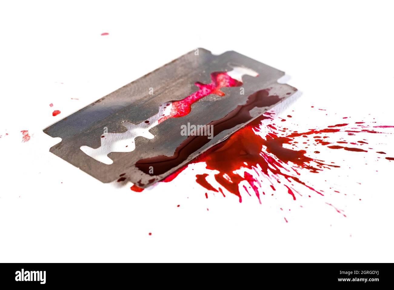 Rasierklinge mit Blutspritzern und Bluttropfen, isoliert auf weißem, selektivem Fokusmakro. Suicide-Konzept Stockfoto