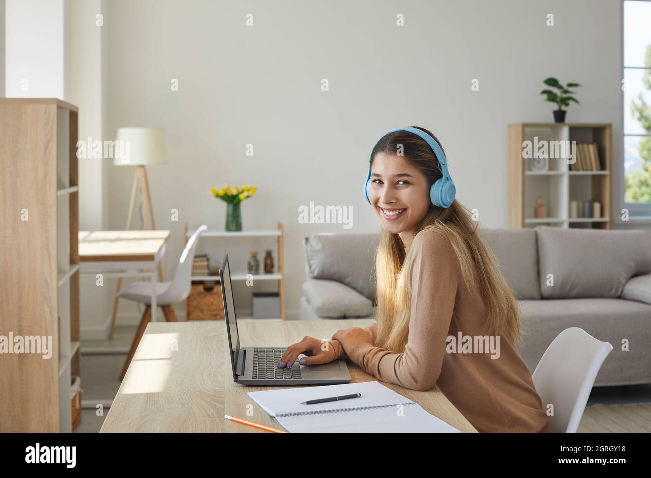 Happy teen Mädchen in Kopfhörer zu Hause Vorbereitung Hausaufgaben sitzen mit Notebook am Laptop. Stockfoto
