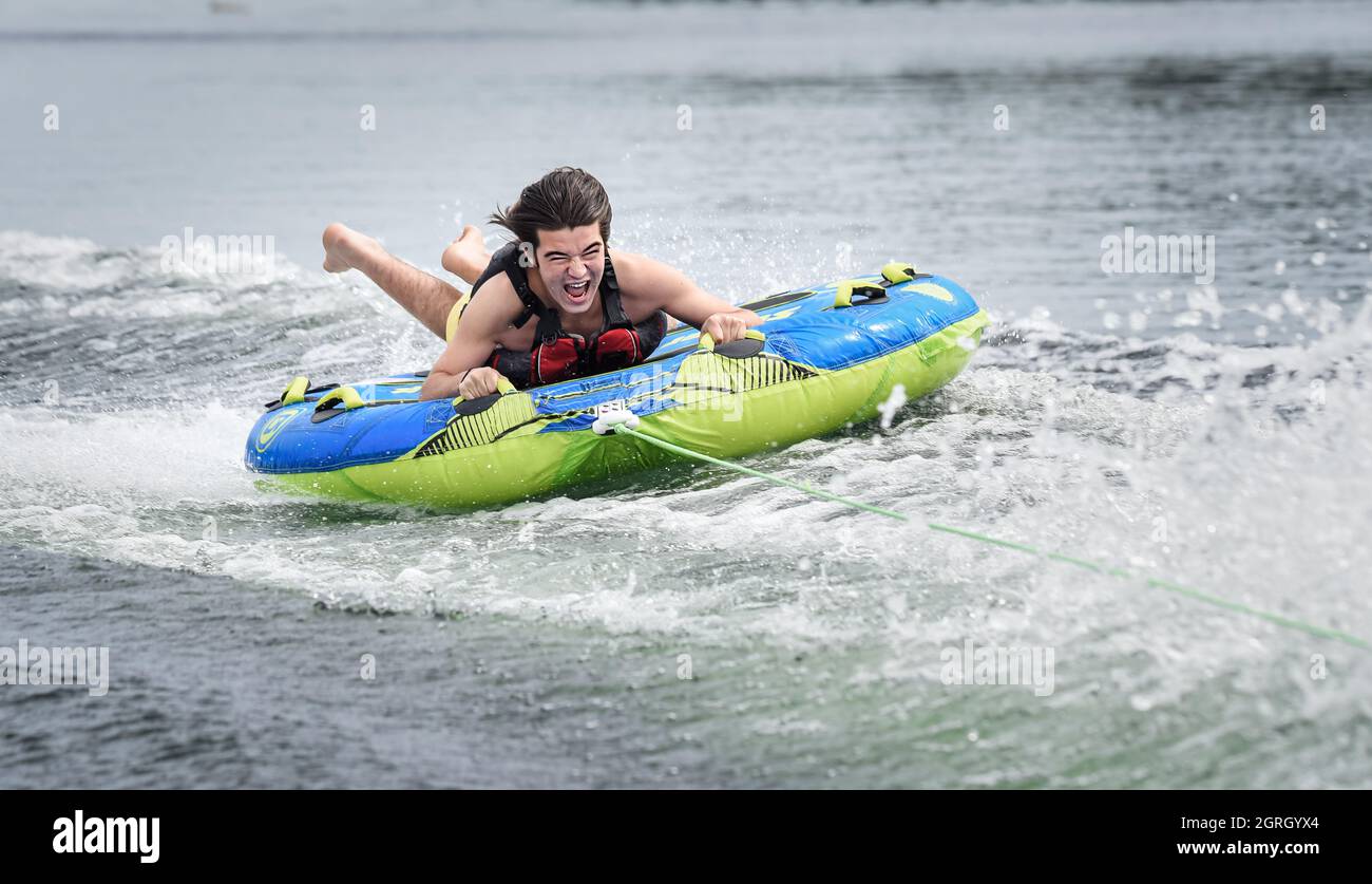 Aufgeregt Teenager Spaß auf einem Rohr von einem Boot auf einem See gezogen. Stockfoto