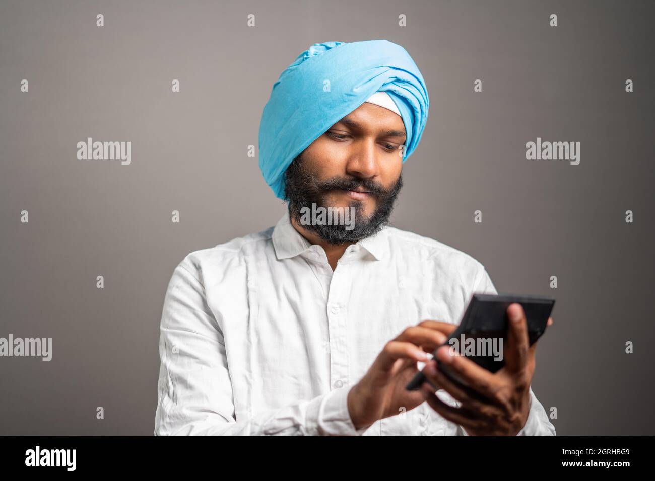 studioaufnahme des jungen sikh-Mannes ernsthaft denken und Berechnung von Steuern oder finanziellen Aufwendungen auf Rechner Stockfoto
