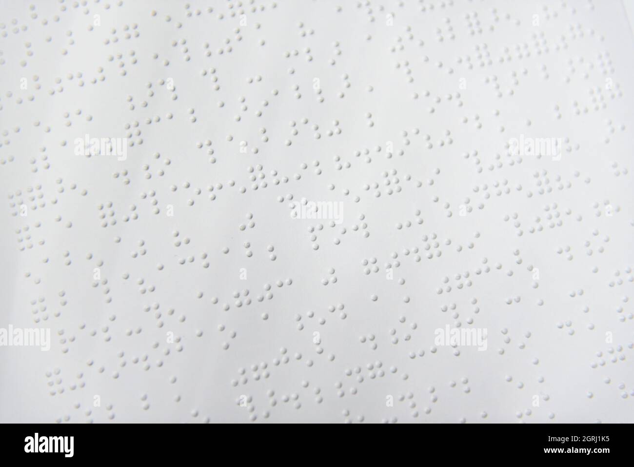 Ein Textfragment in Louis-Braille-Schrift, das mit speziellen Druckgeräten auf ein Standardpapier gedruckt wurde. Stockfoto