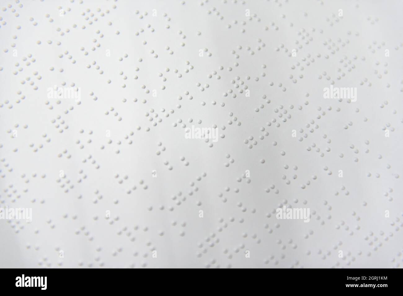 Ein Textfragment in Louis-Braille-Schrift, das mit speziellen Druckgeräten auf ein Standardpapier gedruckt wurde. Stockfoto