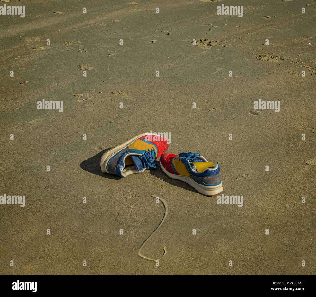 Bunte Turnschuhe liegen verlassen am Strand. Stockfoto