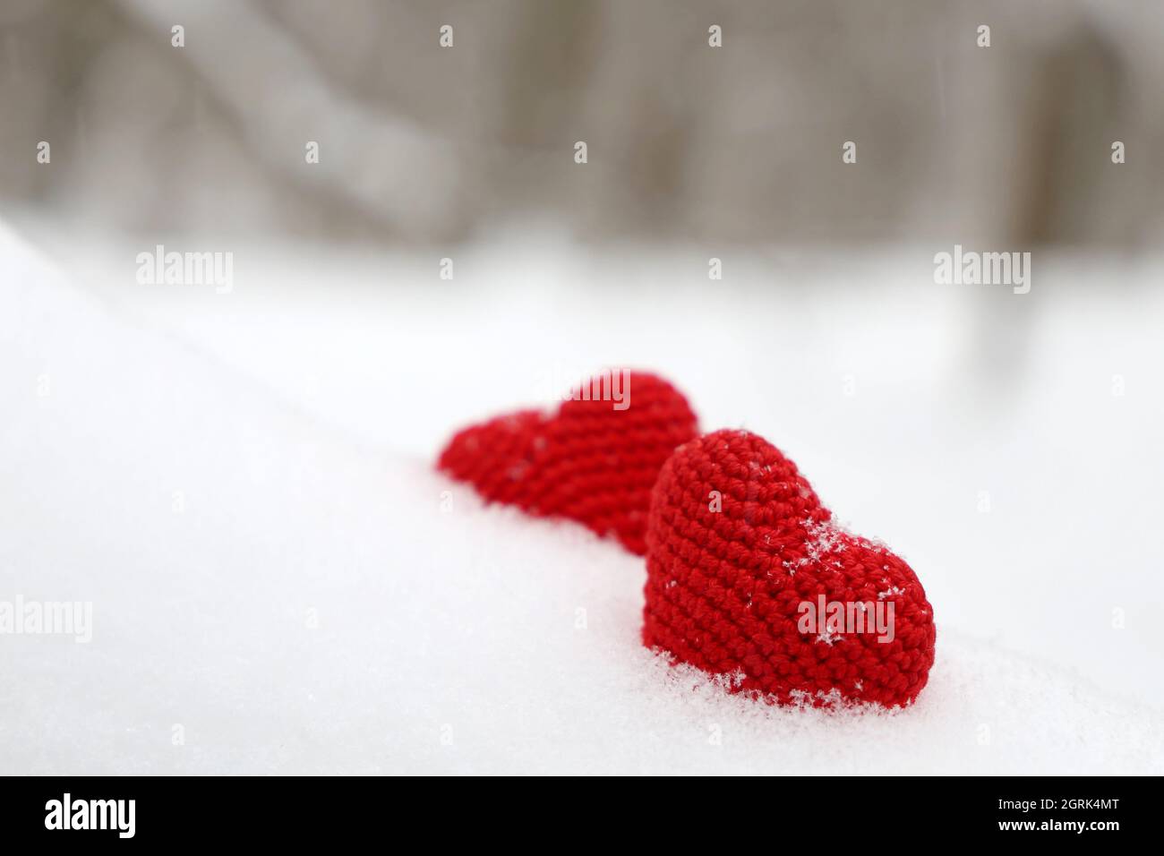 Valentines Herzen im Winterwald. Zwei rote gestrickte Herzen auf Schnee, Symbol der romantischen Liebe, Hintergrund für den Urlaub Stockfoto