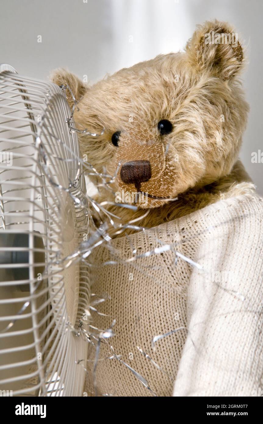 Altmodischer Teddybär vor einem elektrischen Ventilator mit Lametta, der bläst Stockfoto