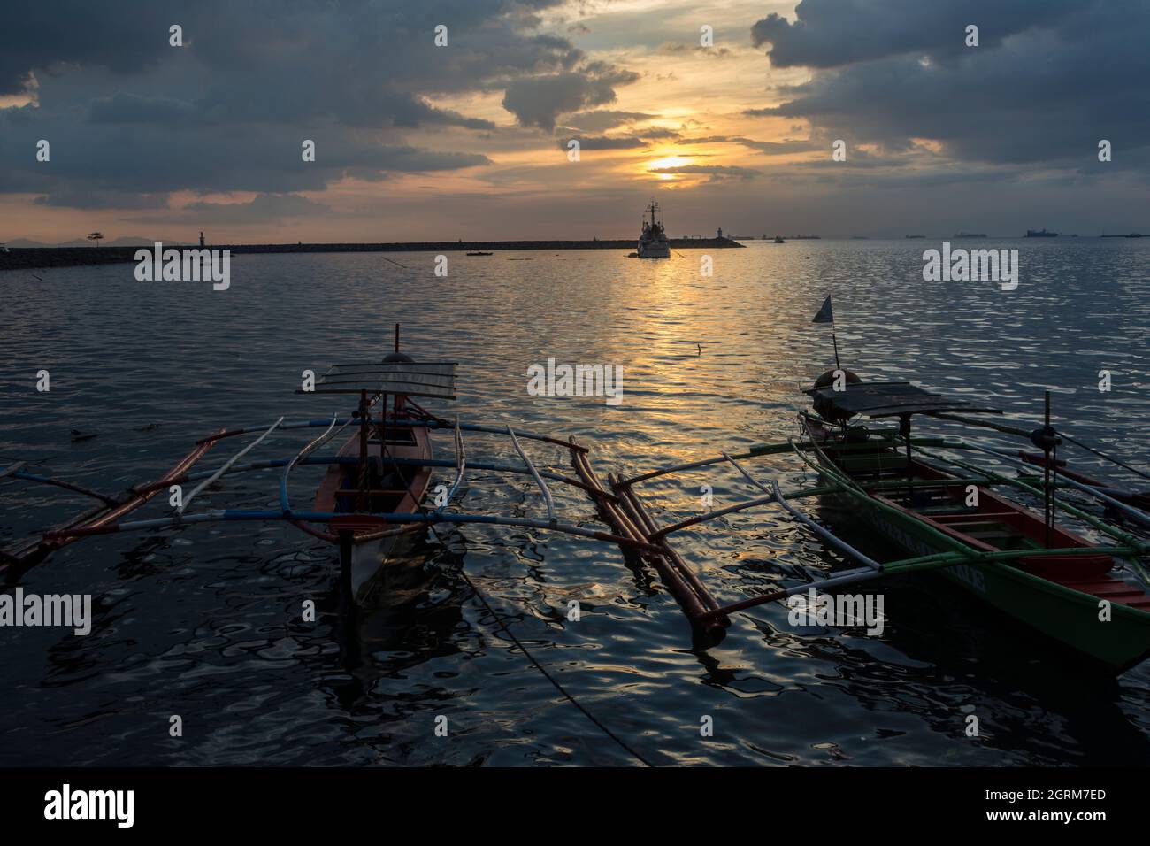 Sonnenuntergang mit zwei Auslegern-Fischerbooten, die am Baywalk in Manila, Philippinen, festgemacht sind. Stockfoto