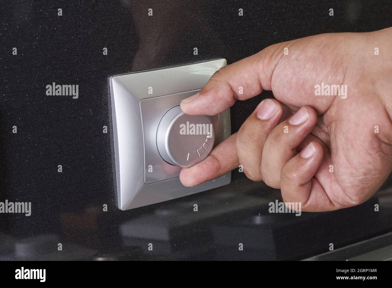 Dimmer-Schalter für elektrisches Licht oder Wärmeregler für Klimaanlage von Hand herunterdrehen Stockfoto