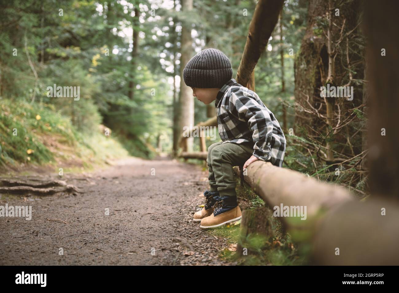Kleines Kind im karierten Hemd und grauem Hut im Wald. Kindheit mit naturliebenden Konzept Stockfoto