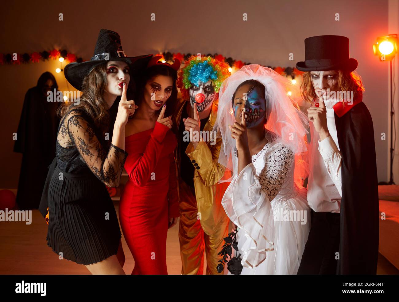 Menschen in Halloween-Kostümen halten die Finger auf den Lippen und bitten dich, über ihre Party zu schweigen Stockfoto