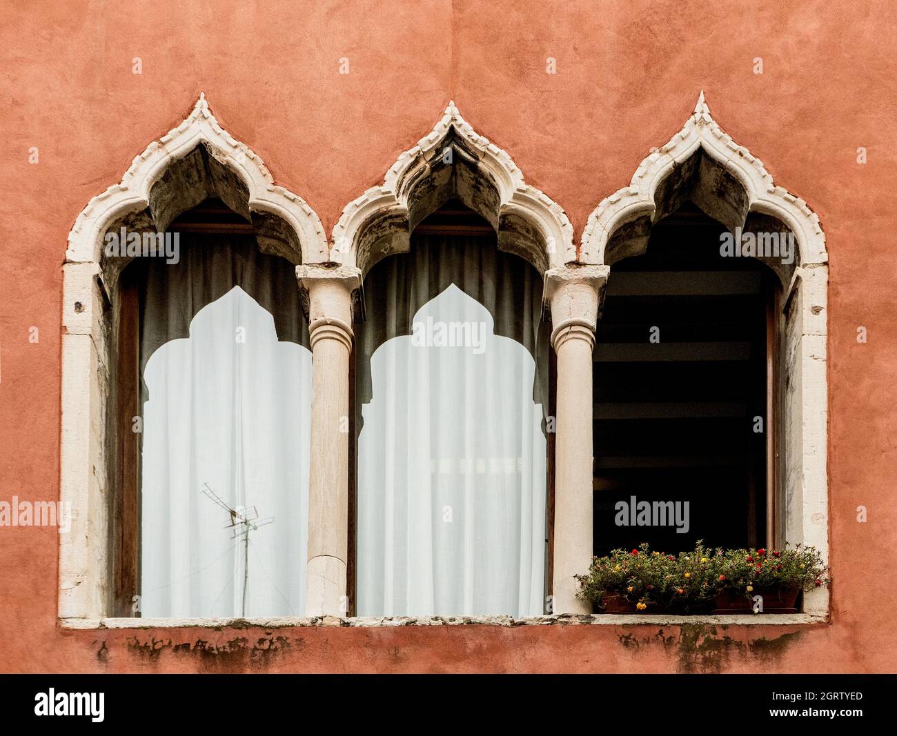 Ein typisches dreibogige Fenster (oder drei-Licht-Fenster) eines Gebäudes, an einer roten Wand, in einer Straße von Venedig, Venetien, Italien, Europa Stockfoto