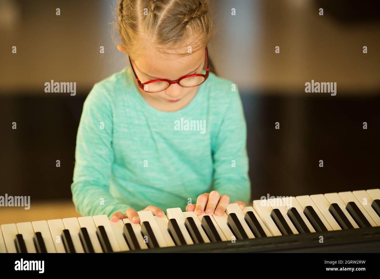 Ein Mädchen mit Down-Syndrom lernt Klavier zu spielen Stockfoto