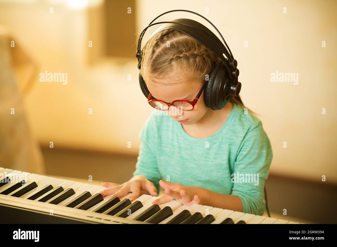 Ein Mädchen mit Down-Syndrom lernt Klavier spielen und hört Musik Stockfoto