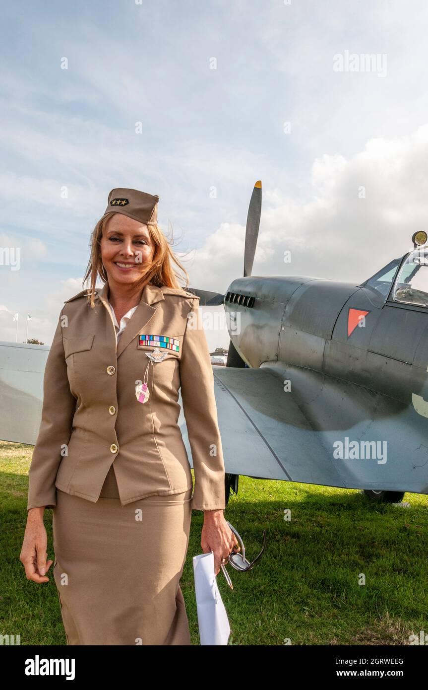 Carol Vorderman MBE im historischen Frauenkostüm der US Air Force, während sie das Flugzeug beim Goodwood Revival 2014 durch eine Spitfire aus dem zweiten Weltkrieg beurteilte Stockfoto