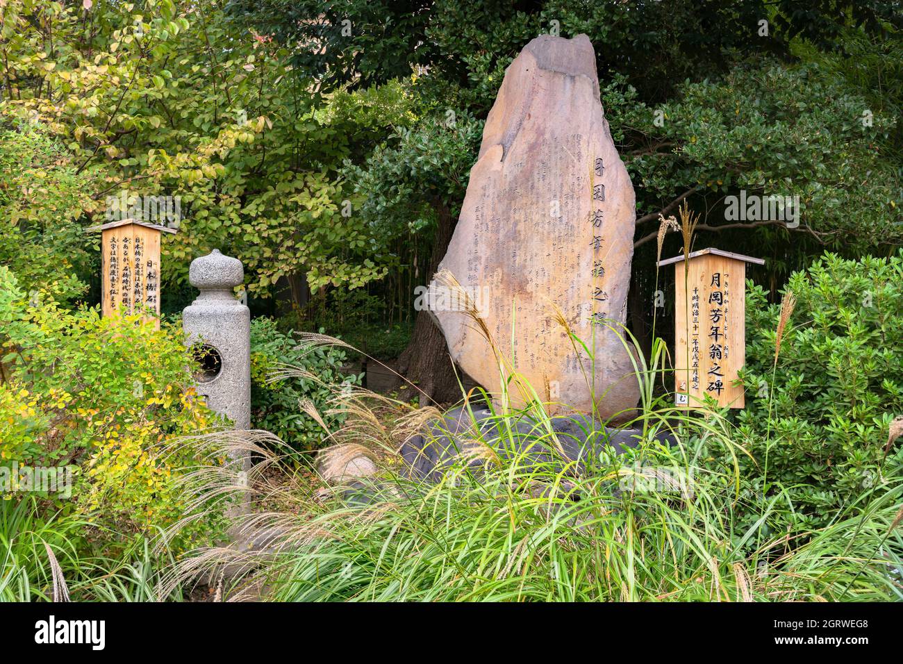 tokio, japan - november 13 2020: Todesgedicht auf einer japanischen Steinstele, die dem Ukiyo-e-Grafiker Tsukioka Yoshitoshi gewidmet ist, und einer Replik einer Säule von Stockfoto