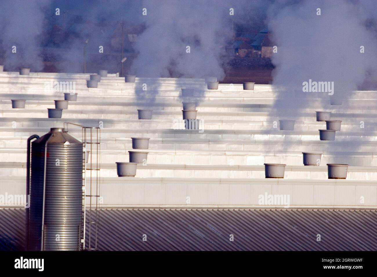 Schornsteine mit dunklem Rauch auf dem Dach eines Industriegebäudes Stockfoto