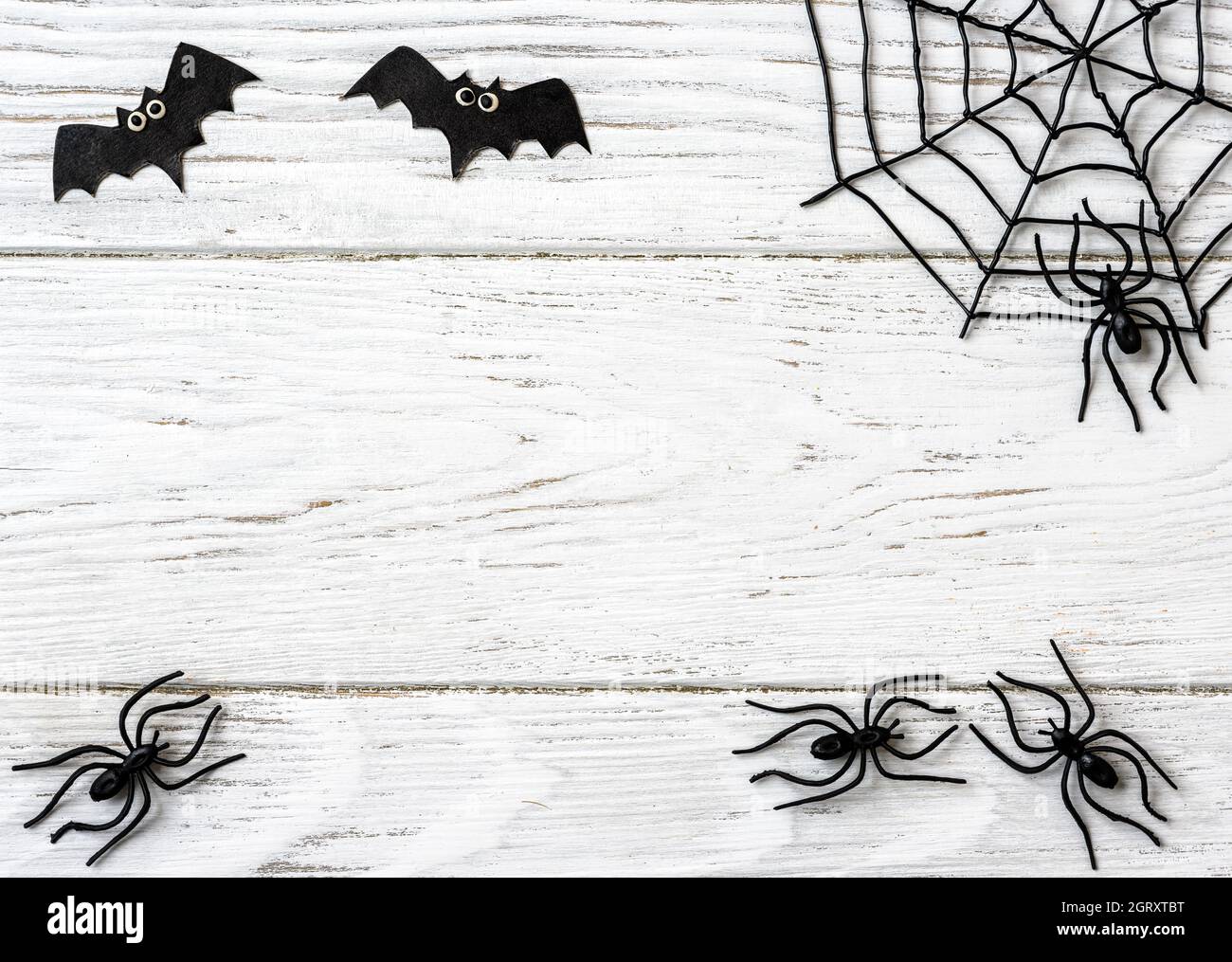 Halloween Hintergrund mit Spinnen, Web und Fledermäuse, Draufsicht. Halloween-Objekte auf weißem Holztisch mit Platz für Text, flach liegend. Minimalistisches Hallowen Stockfoto