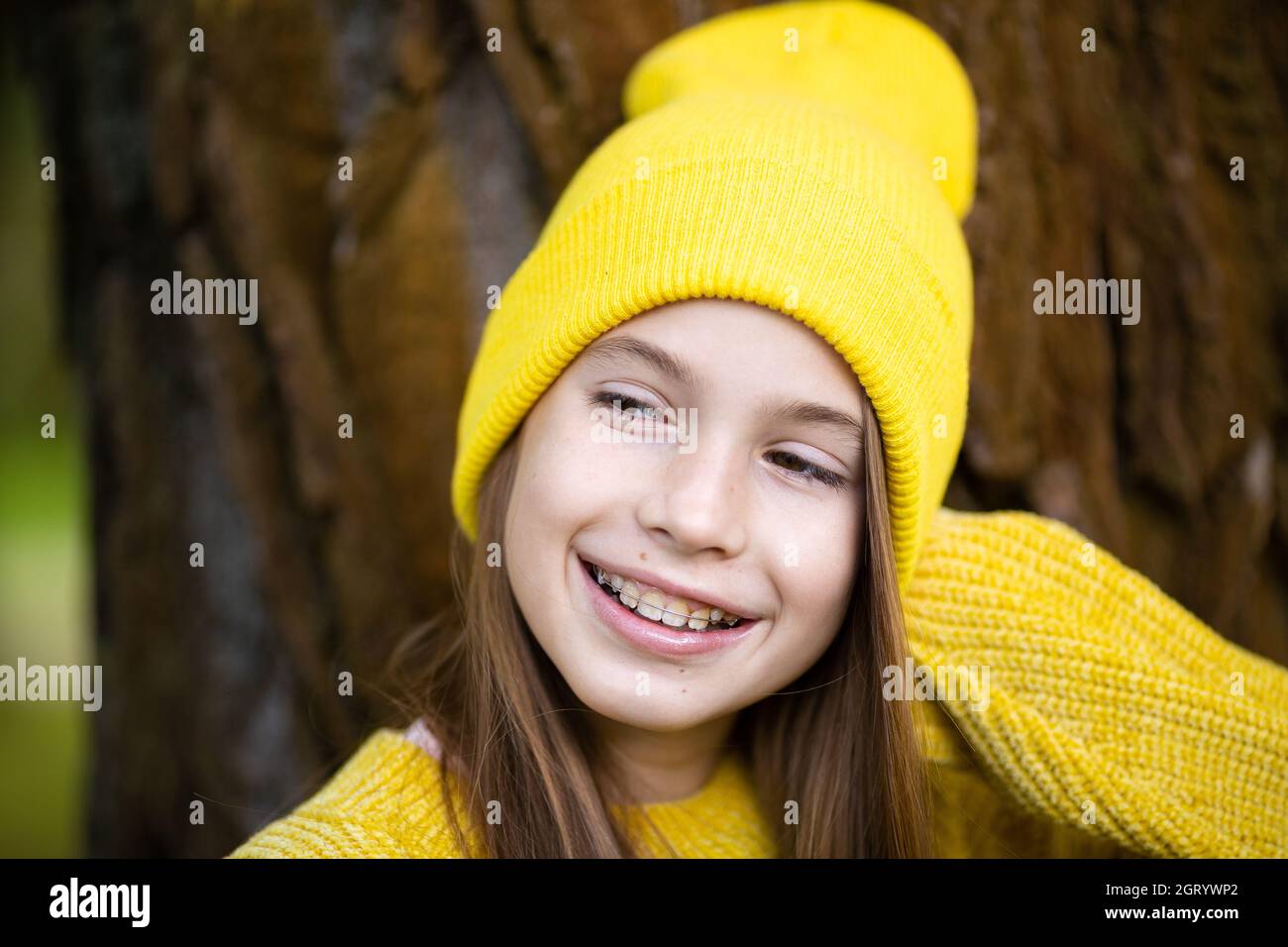 Portrait von modernen glücklichen Teenager-Mädchen mit Zahnspangen in gelben Kleidern im Park gekleidet. Hübsches Teenager-Mädchen mit Zahnspangen lächelt fröhlich. kinderg.a. Stockfoto