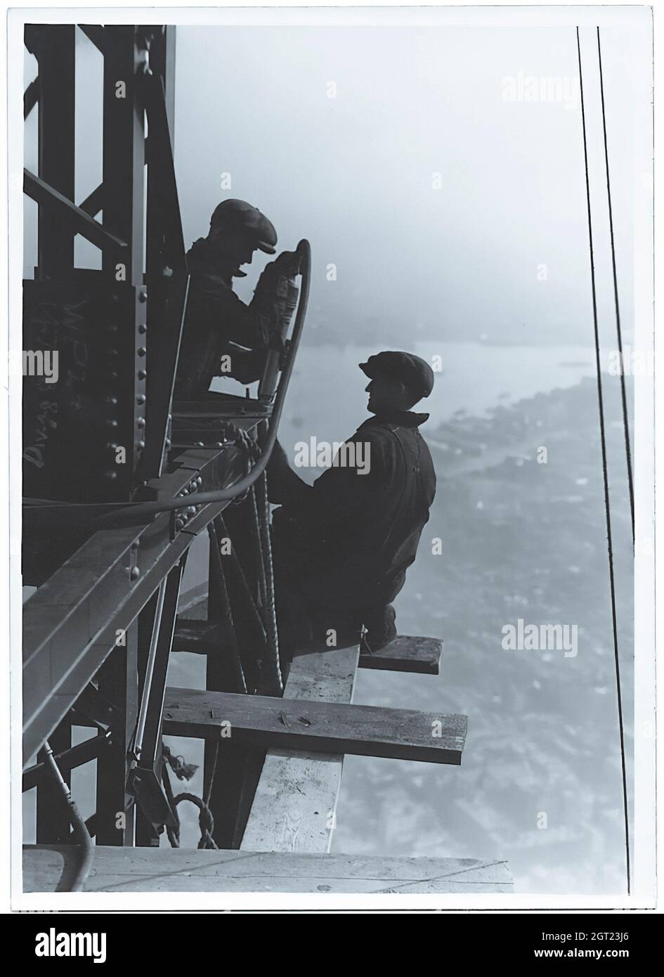 EMPIRE STATE BUILDING NY, NY 1930 - 1931. Allgemeine und detaillierte Ansichten des im Bau befindlichen Empire State Building, in denen Arbeiter verschiedene Aufgaben wie das Positionieren, Schweißen und Nieten von Stahl, das Heben von Materialien und Hilfsgütern sowie das Betreiben und Reparieren von Maschinen zeigen. Es gibt auch eine Vogelperspektive auf Midtown Manhattan, die andere Gebäude zeigt, die im Bau sind. Fotografien von: Hine, Lewis Wickes, 1874-1940 . Stockfoto