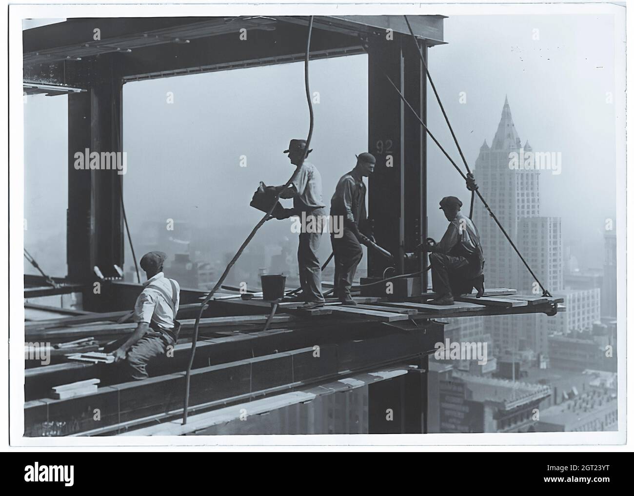 EMPIRE STATE BUILDING NY, NY 1930 - 1931. Allgemeine und detaillierte Ansichten des im Bau befindlichen Empire State Building, in denen Arbeiter verschiedene Aufgaben wie das Positionieren, Schweißen und Nieten von Stahl, das Heben von Materialien und Hilfsgütern sowie das Betreiben und Reparieren von Maschinen zeigen. Es gibt auch eine Vogelperspektive auf Midtown Manhattan, die andere Gebäude zeigt, die im Bau sind. Fotografien von: Hine, Lewis Wickes, 1874-1940 . Stockfoto