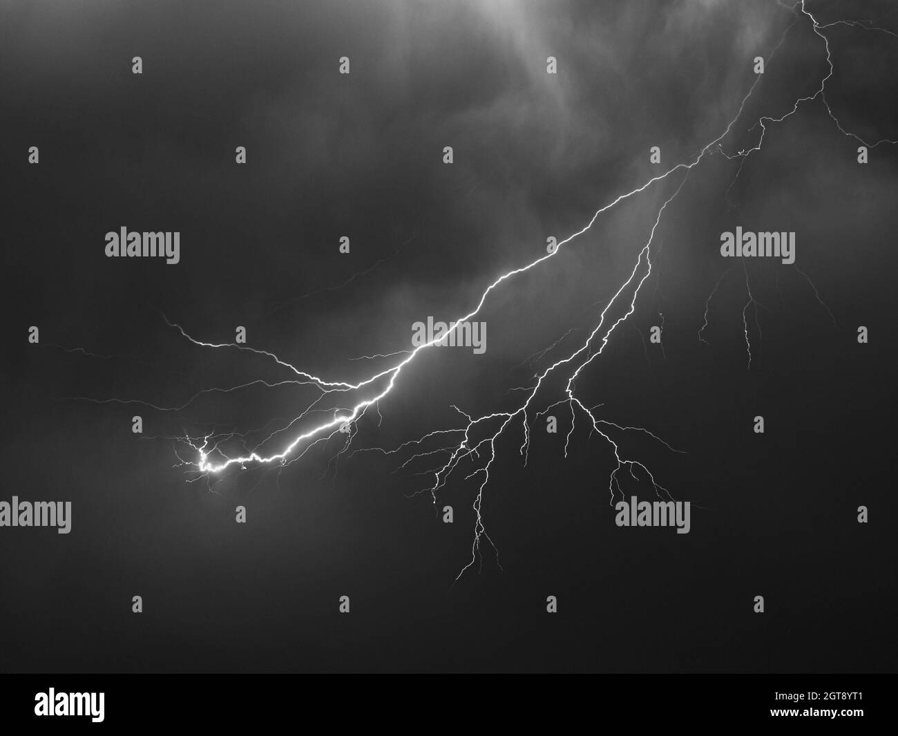 Blitzschlag mit vielen Seitenzweigen hoch oben am Himmel. Schwarzweiß-Bild. Stockfoto