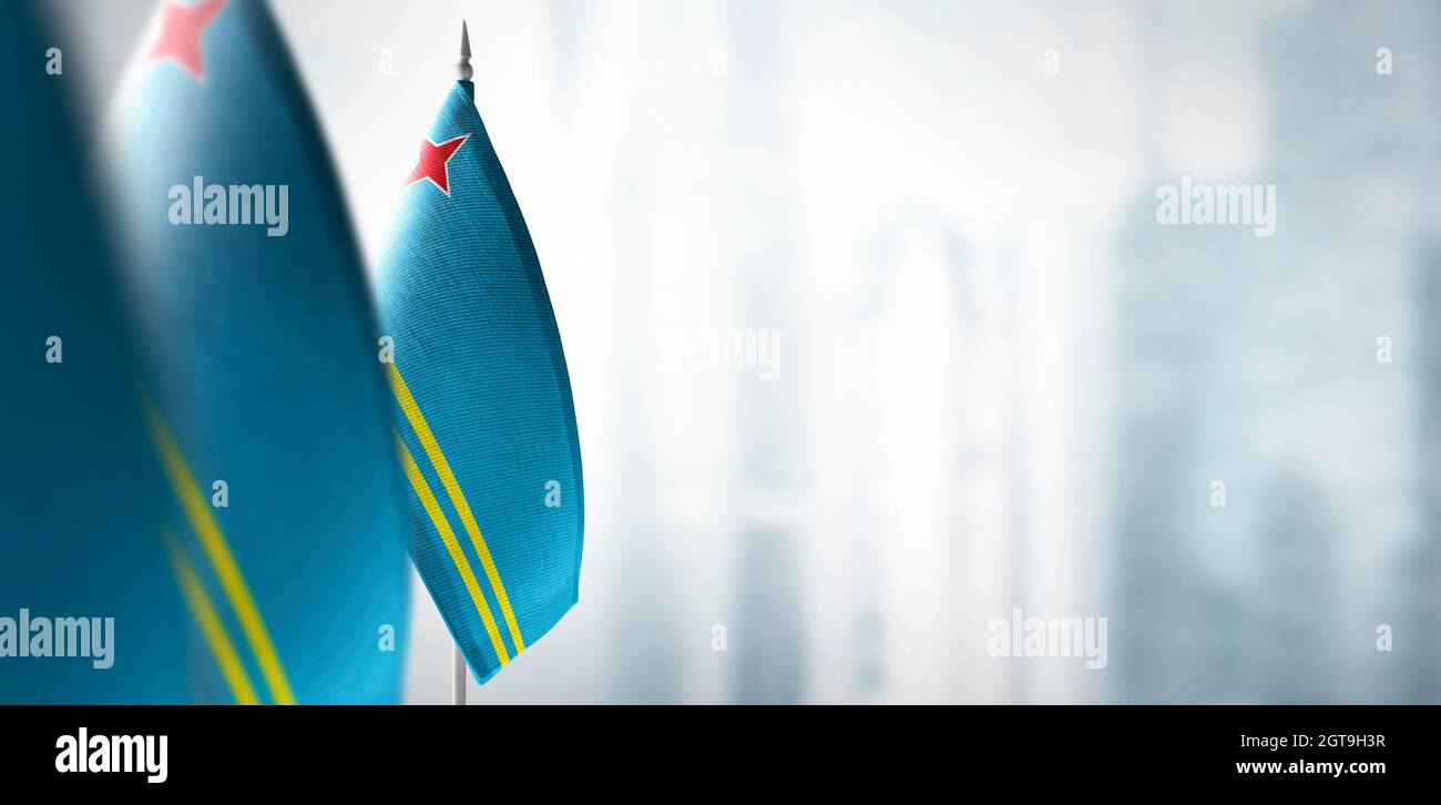 Kleine Flaggen von Aruba auf einem verschwommenen Hintergrund der Stadt Stockfoto