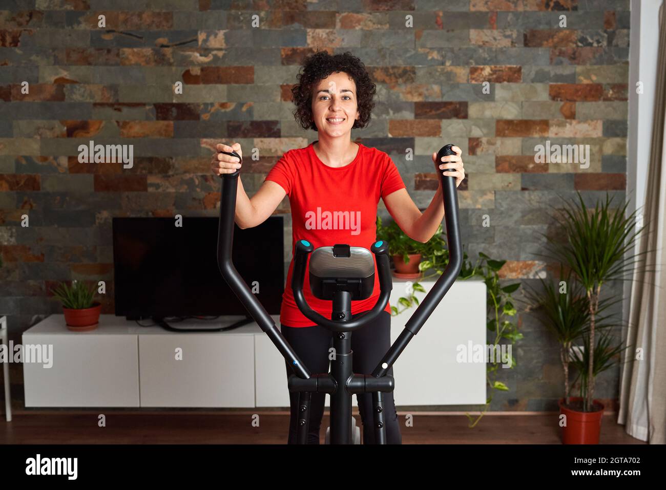 Frau trainiert zu Hause mit einem Crosstrainer Stockfoto